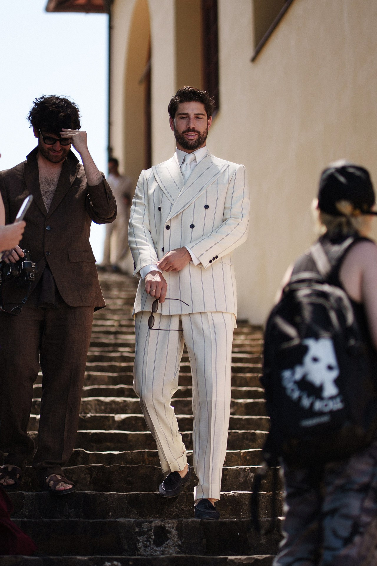 Street style da Pitti Uomo 110, ospite in completo bianco gessato sulle scale a Firenze