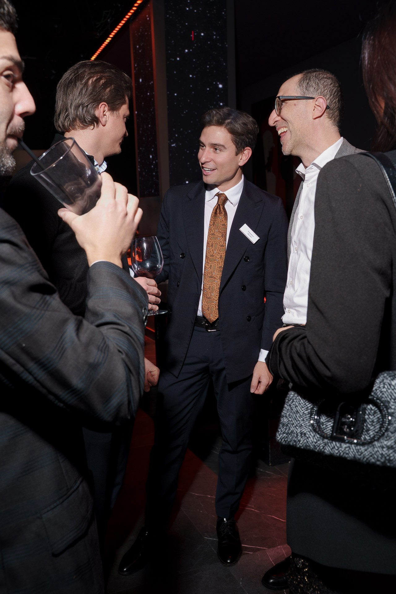 Professional business guests networking and enjoying a cocktail reception during a corporate event in Milan, capturing authentic interaction.