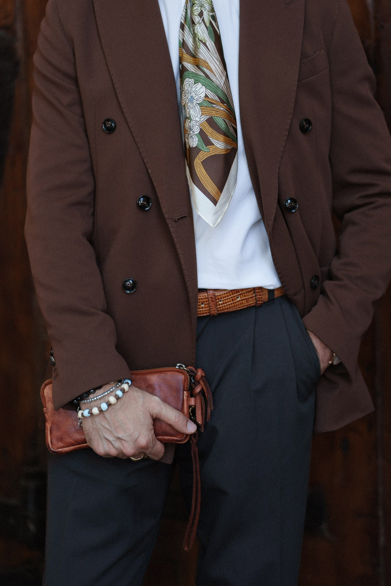 Dettaglio da Pitti Uomo 110, blazer marrone, cravatta fantasia, bracciali e clutch in pelle
