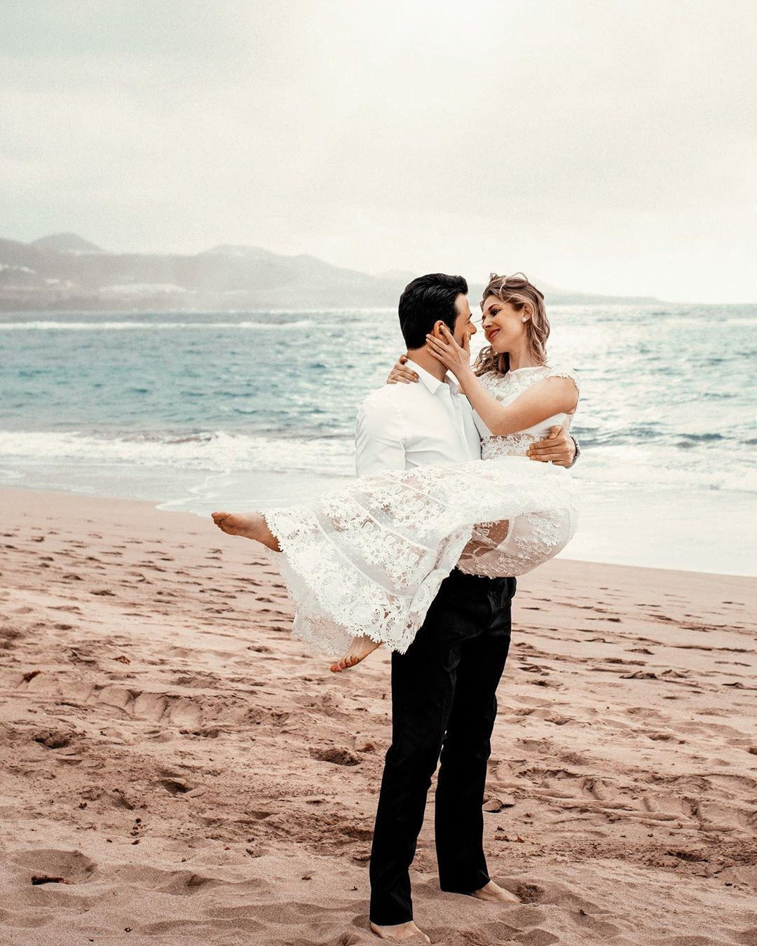 Une mariée et un marié s'enlaçant sur la plage lors de leur fugue.