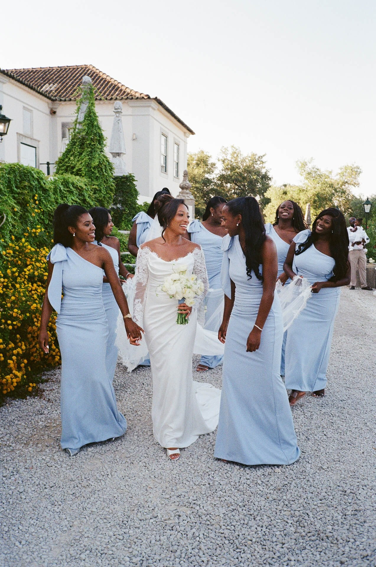 Bride walking with bridesmaids along villa exterior destination wedding