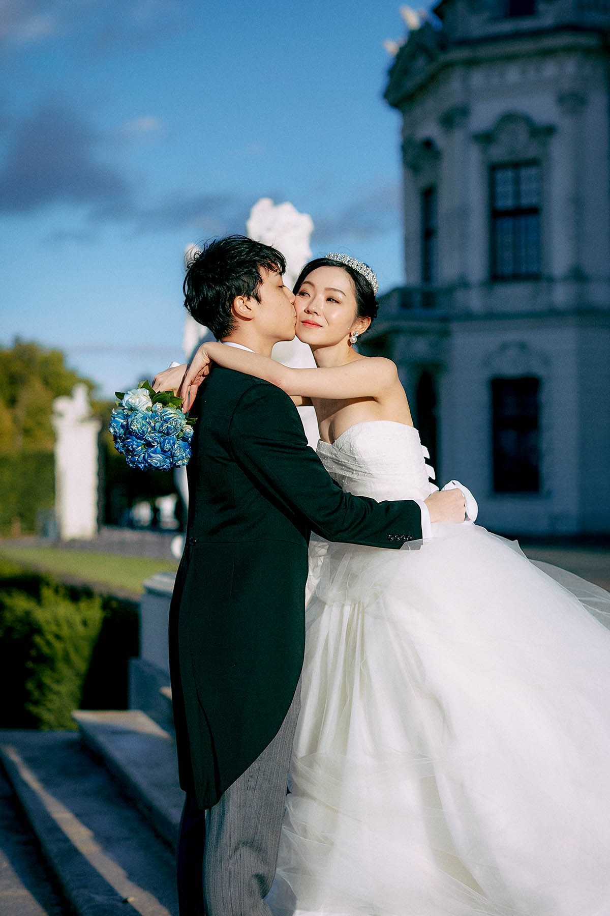 Happy bride embracing groom facing camera Belvedere gardens.
