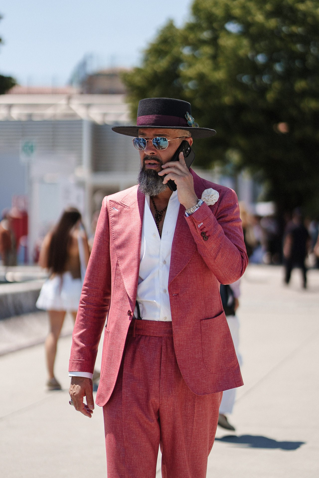 Ritratto street style da Pitti Uomo 110, ospite in completo rosso e cappello nero mentre parla al telefono