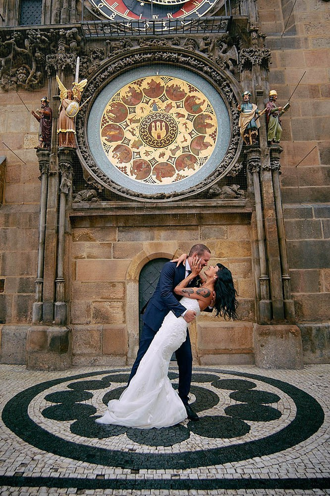 Bride kissing groom passionately during dip under the Astronomical Clock.