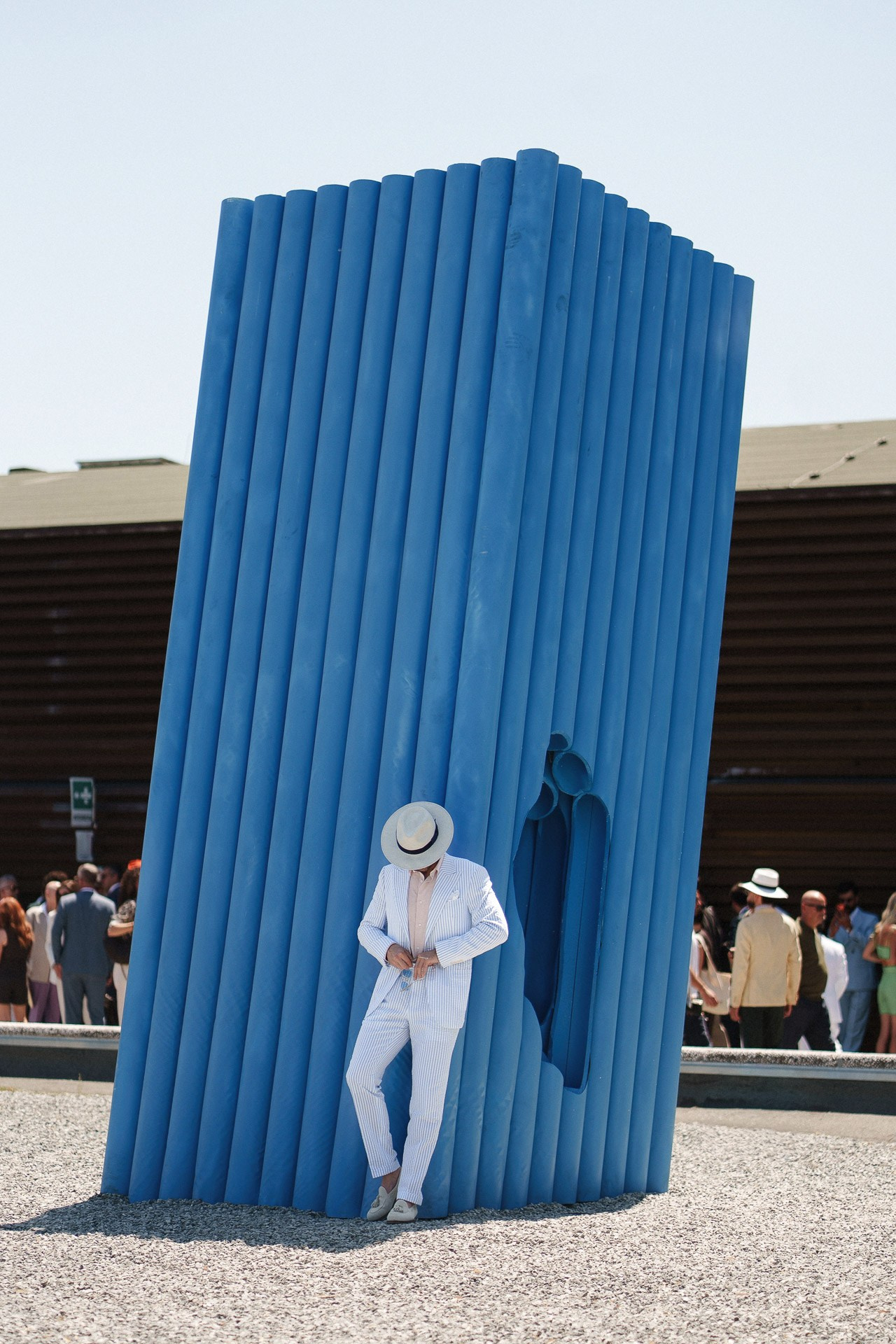 Scena street style da Pitti Uomo 110, ospite in completo azzurro a righe dentro l’installazione blu
