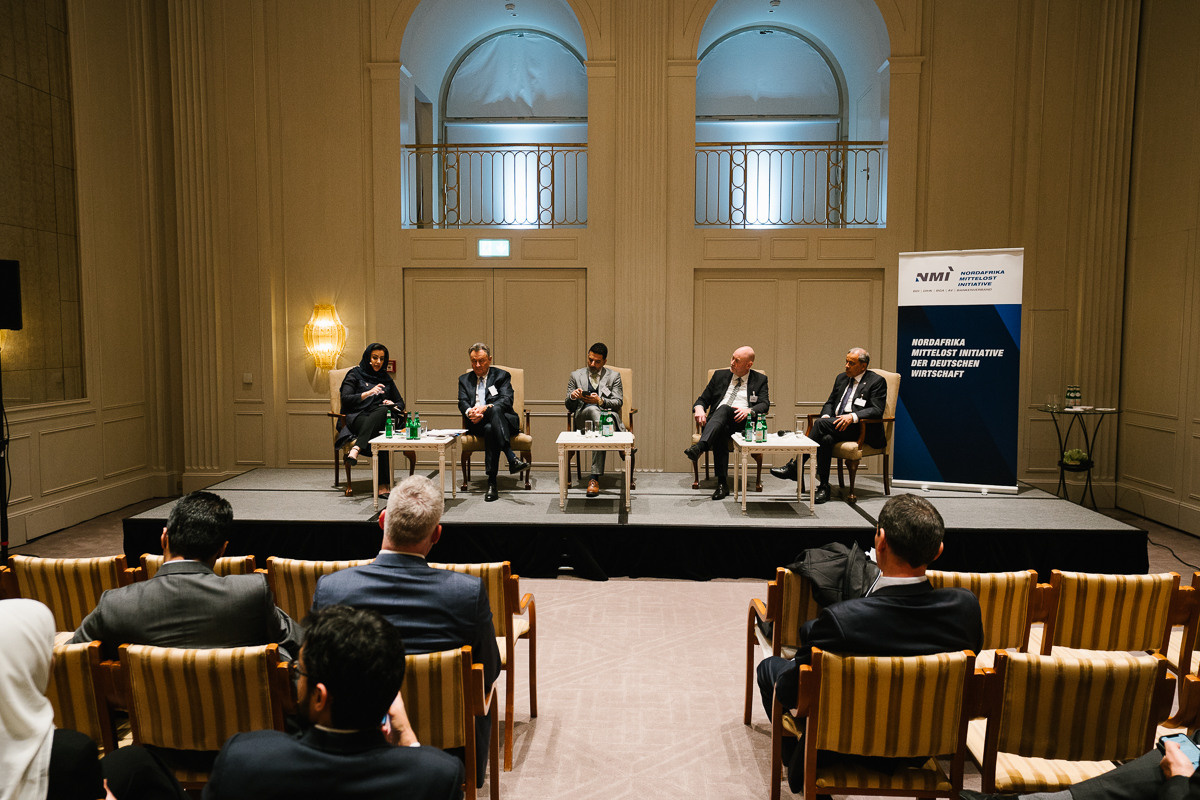 Audience listens to an expert panel on stage in an elegant conference hall
