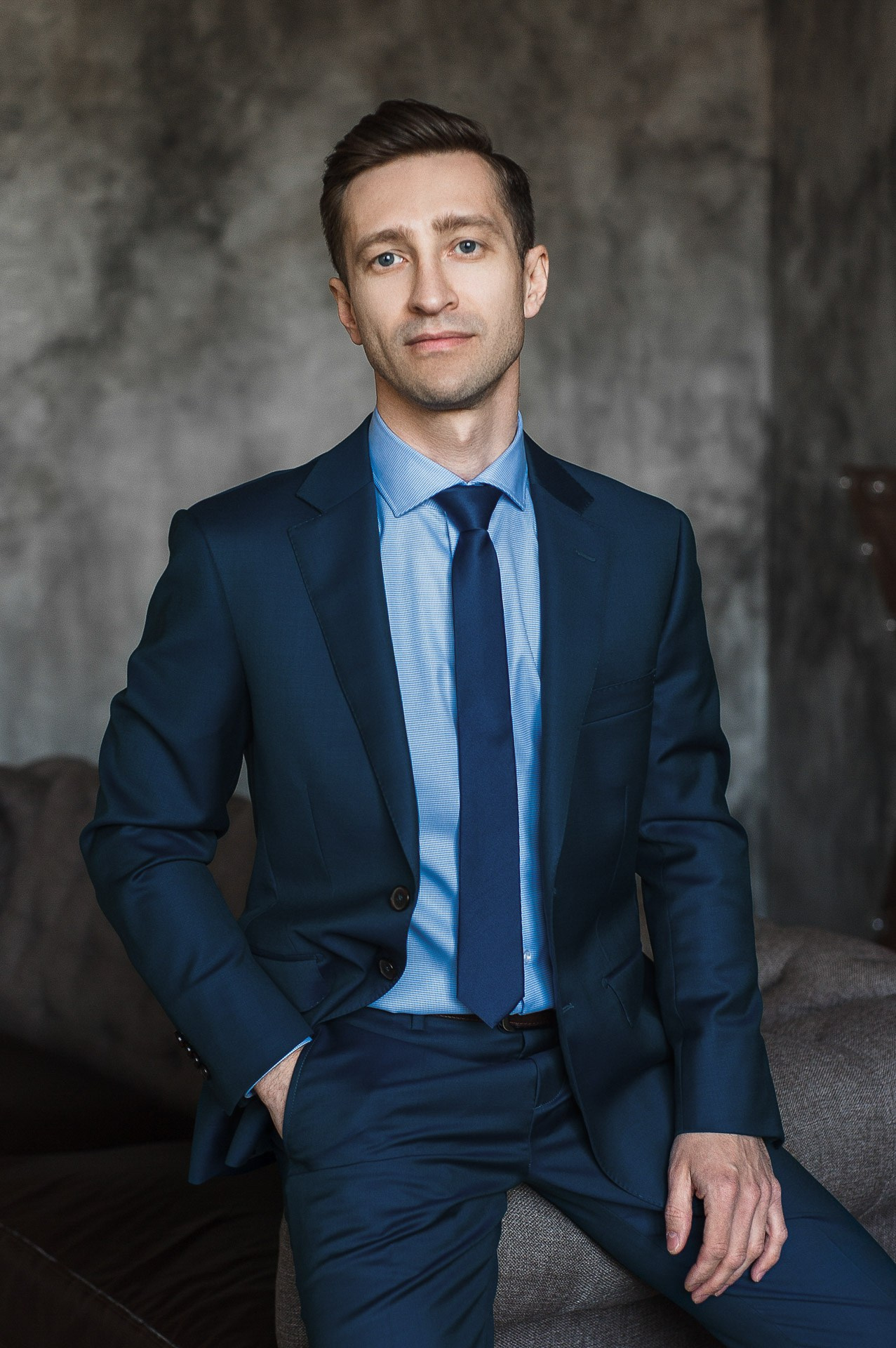 Modern corporate headshot of a professional man in a dark blue suit and tie, Milan business photography.