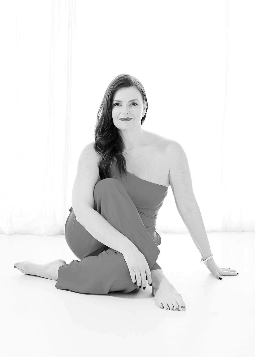 BLACK AND WHITE IMAGE OF WOMAN SITTING CROSS LEGGED ON FLOOR