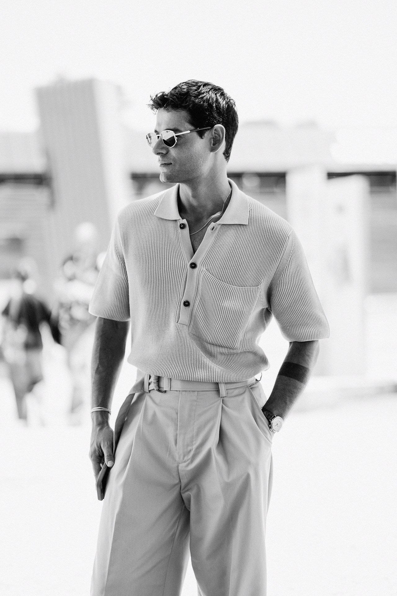 Ritratto in bianco e nero da Pitti Uomo 110, ospite in polo leggera in maglia e pantaloni con pinces a Firenze