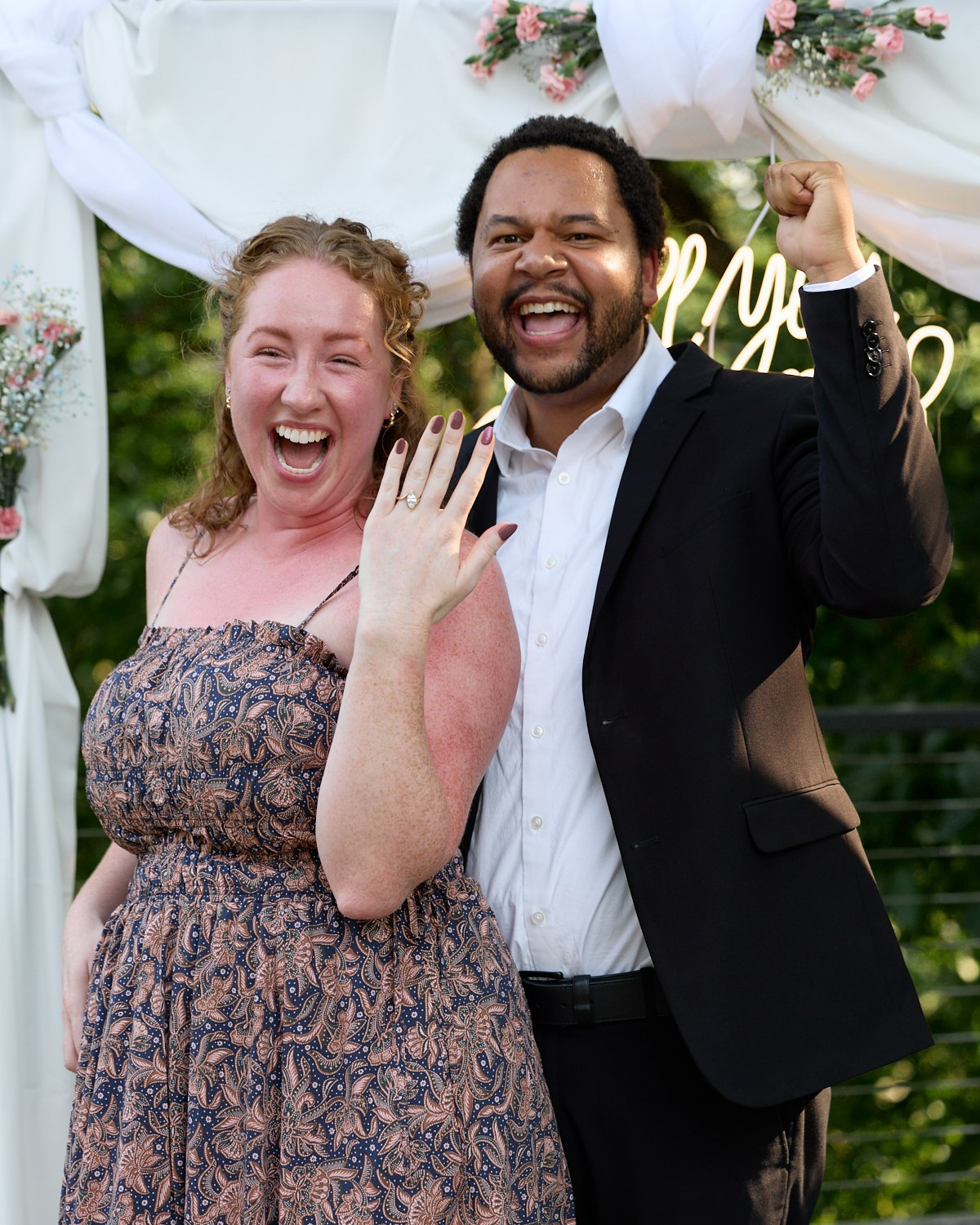Laughing couple celebrating under the proposal arch in Dublin, Ohio