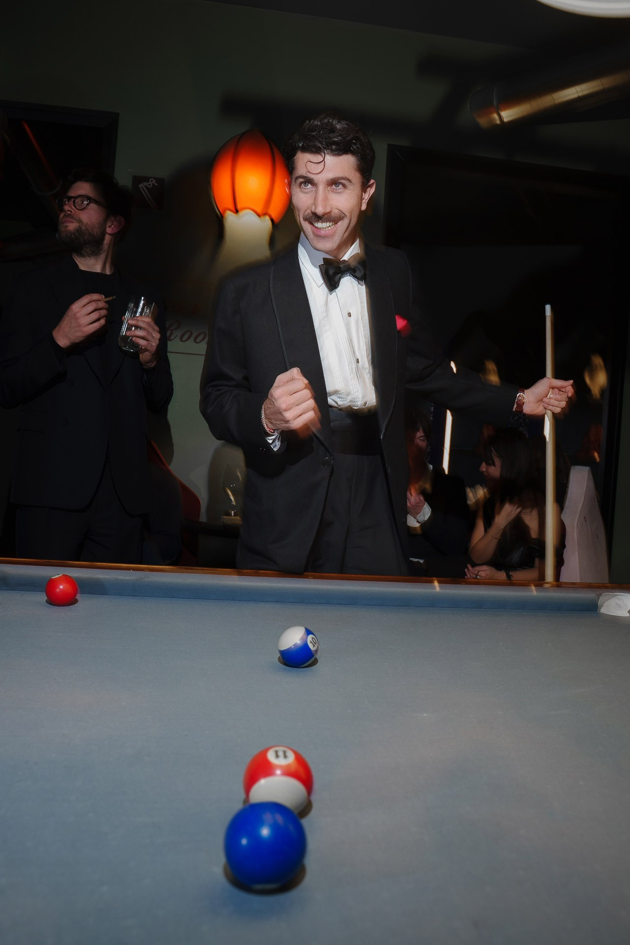 Man in black tuxedo playing billiards during evening luxury event