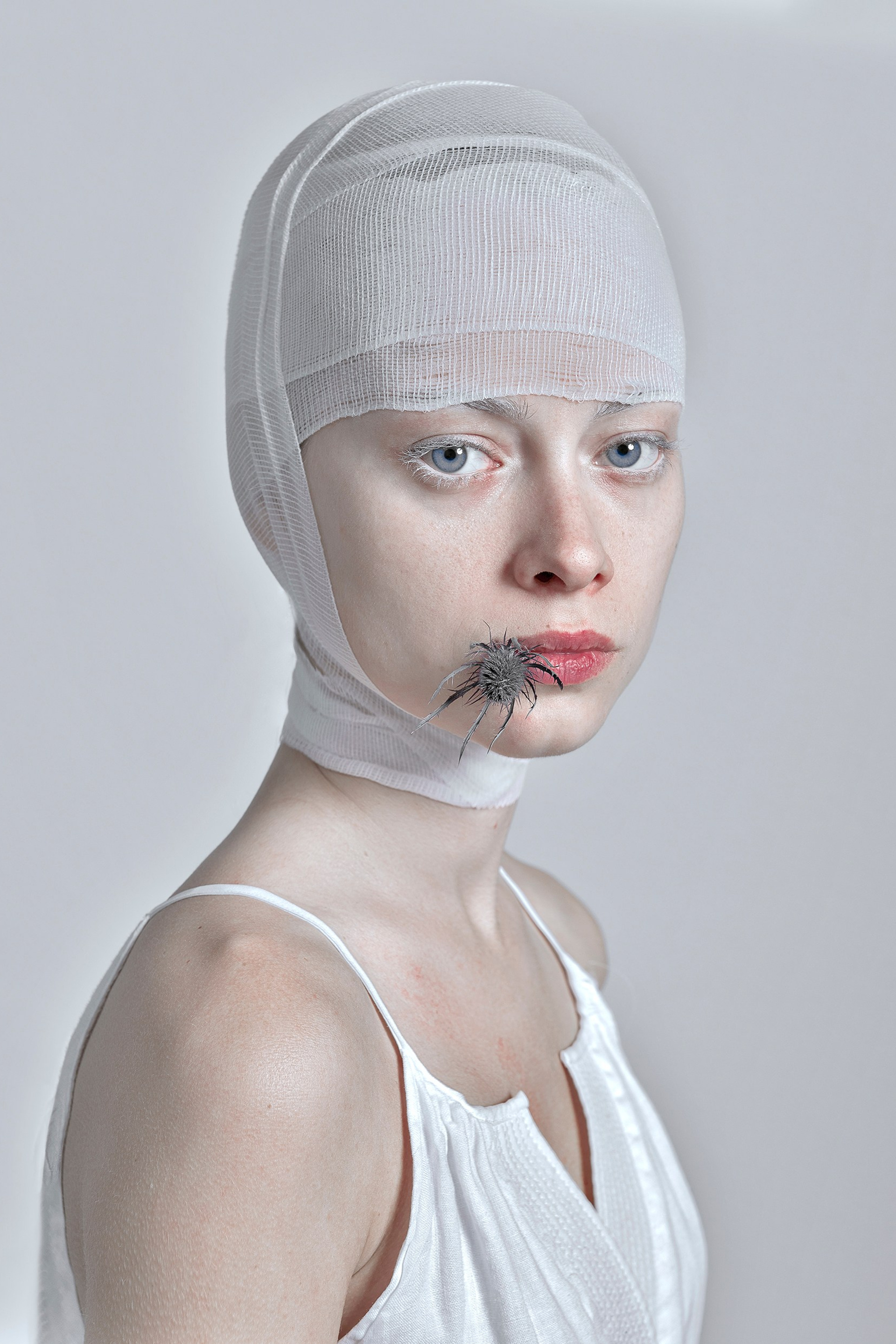 Woman with head bandage and thistle, embodying resilience and healing.
