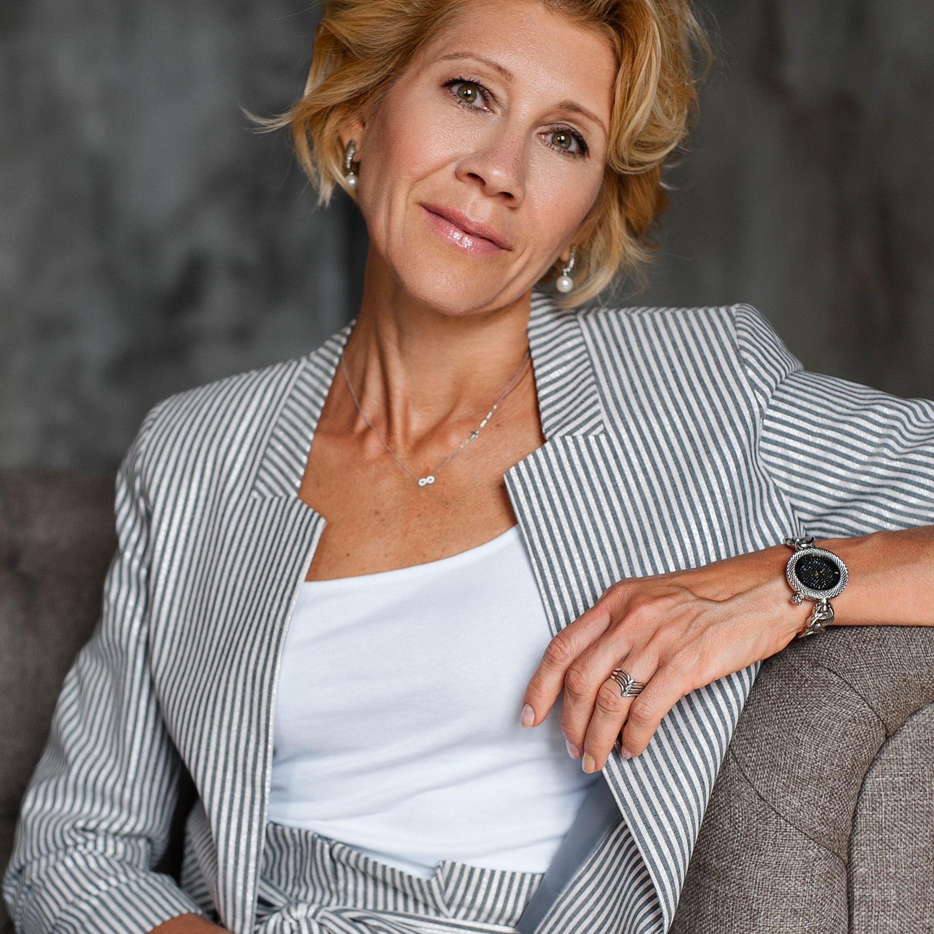 Elegant businesswoman in a striped blazer seated on a sofa, combining style and professionalism in corporate branding