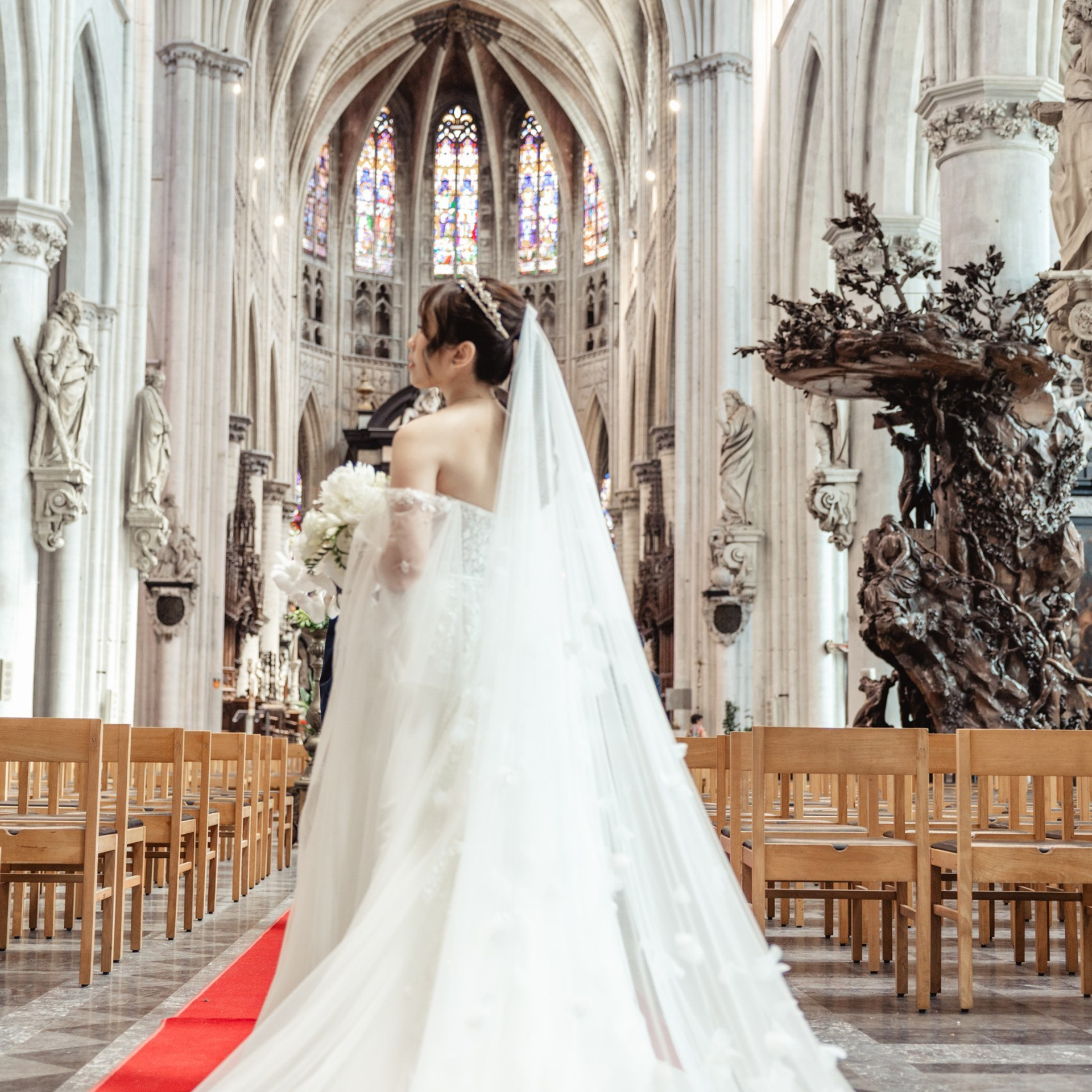 Bruid staat in de kerk terwijl haar jurk uitvalt over het gangpad