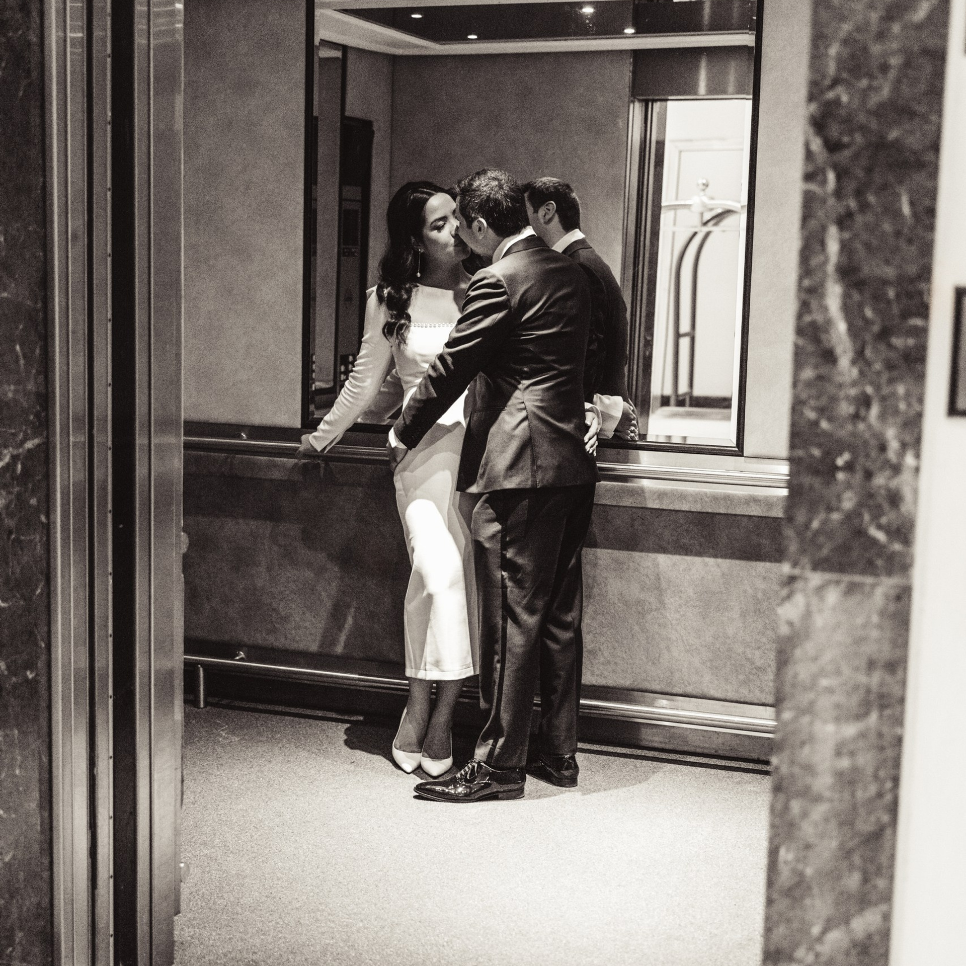 Bruidspaar staat dicht bij elkaar in een lift in zwart-wit
