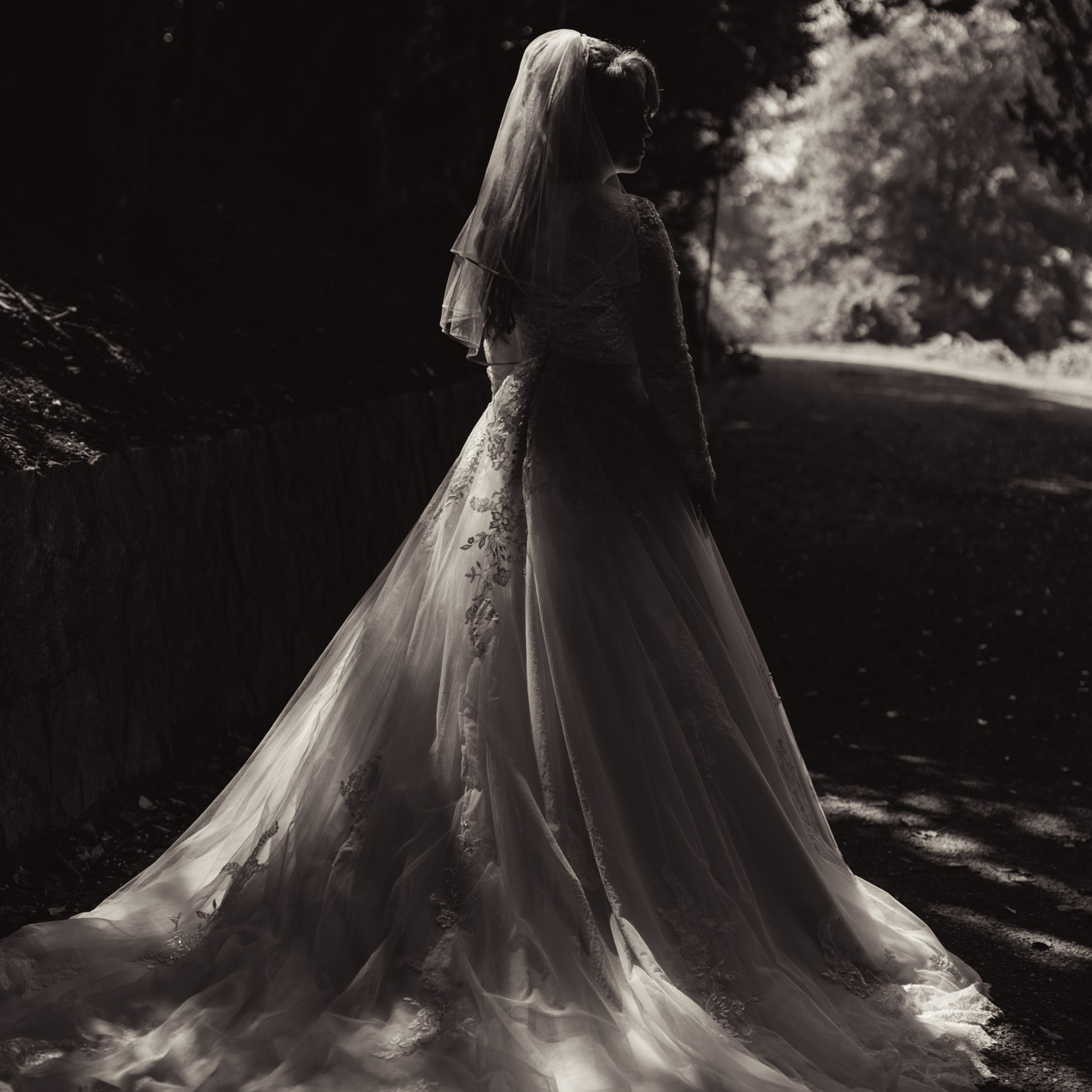 Bruid staat buiten in haar trouwjurk