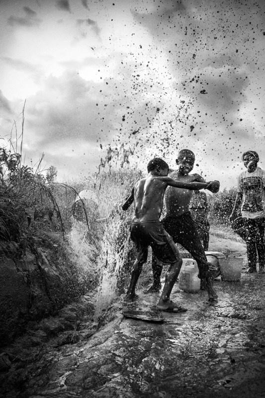 Crack in the water network: free for a moment, the children take advantage and dance, Fianarantsoa, Republic of Madagascar. 2014