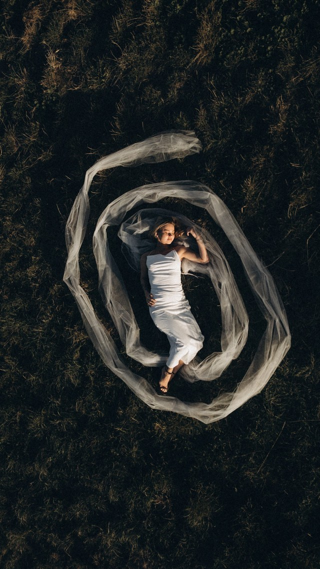 Sposa vista dall’alto distesa nel velo durante un matrimonio intimo, fotografia artistica con drone in stile romantico, Rimini Emilia-Romagna