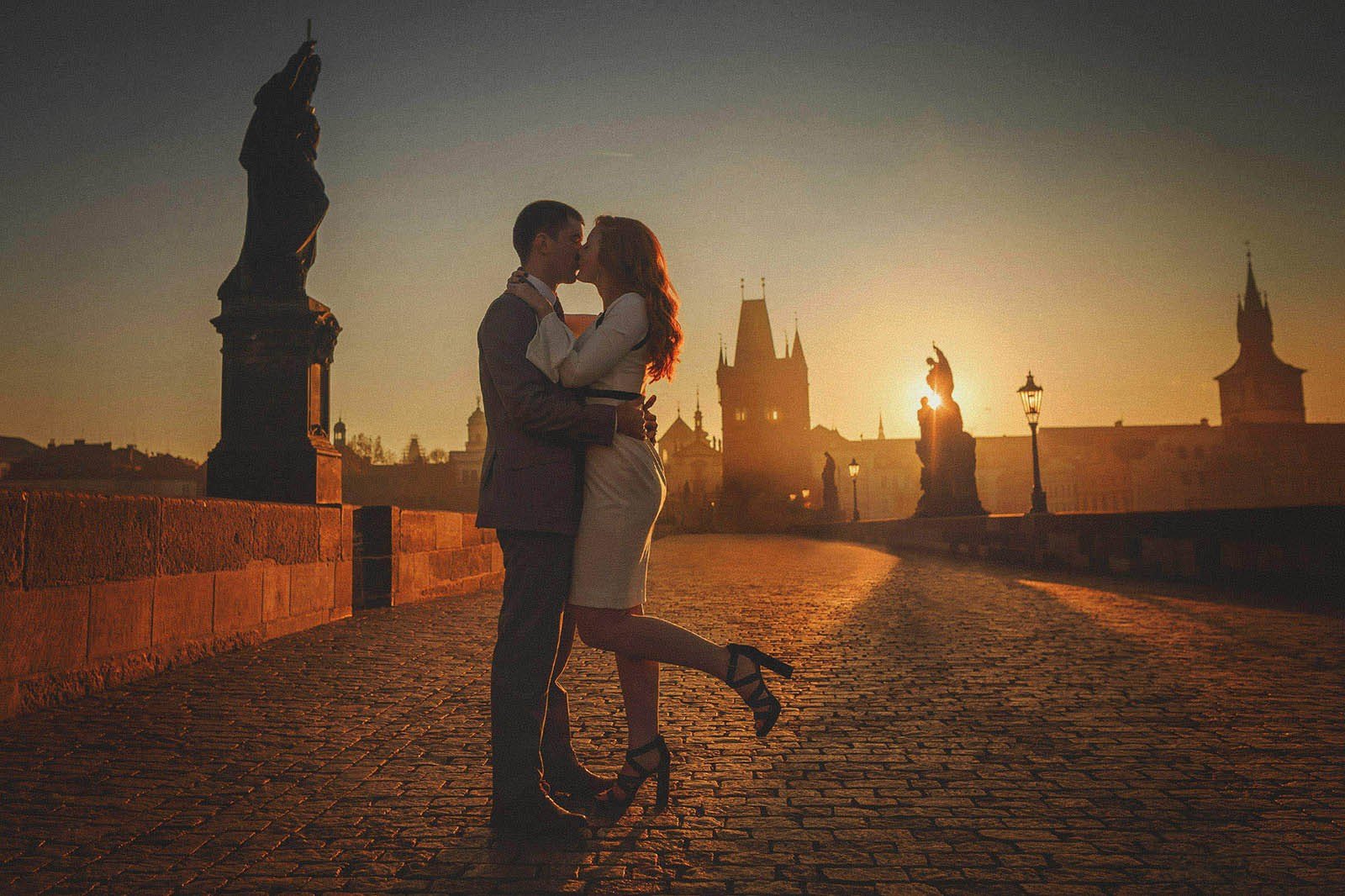 Silhouette of a couple kissing atop Charles Bridge at sunrise all alone