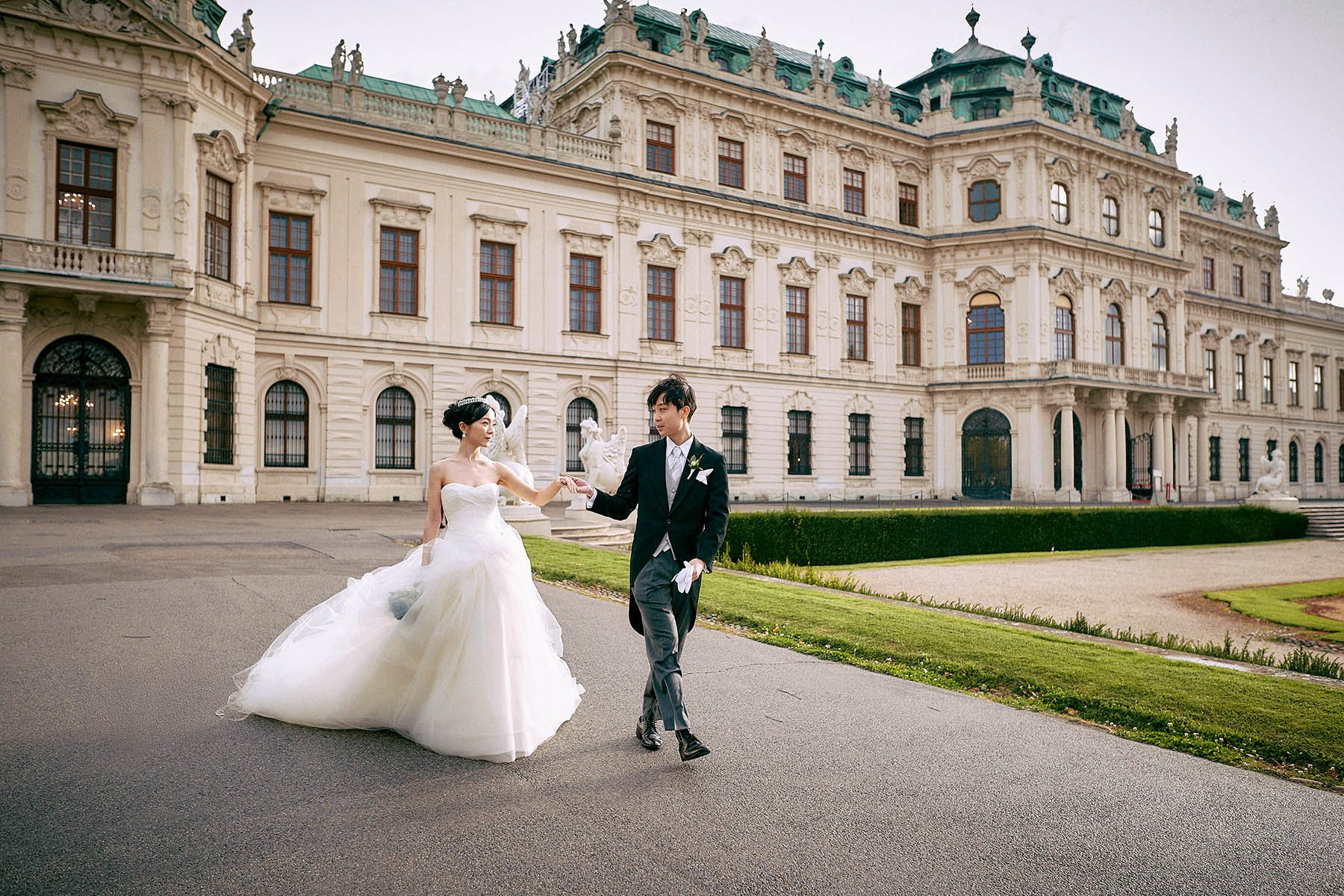Bride's dress blowing in wind while walking Belvedere Palace gardens.