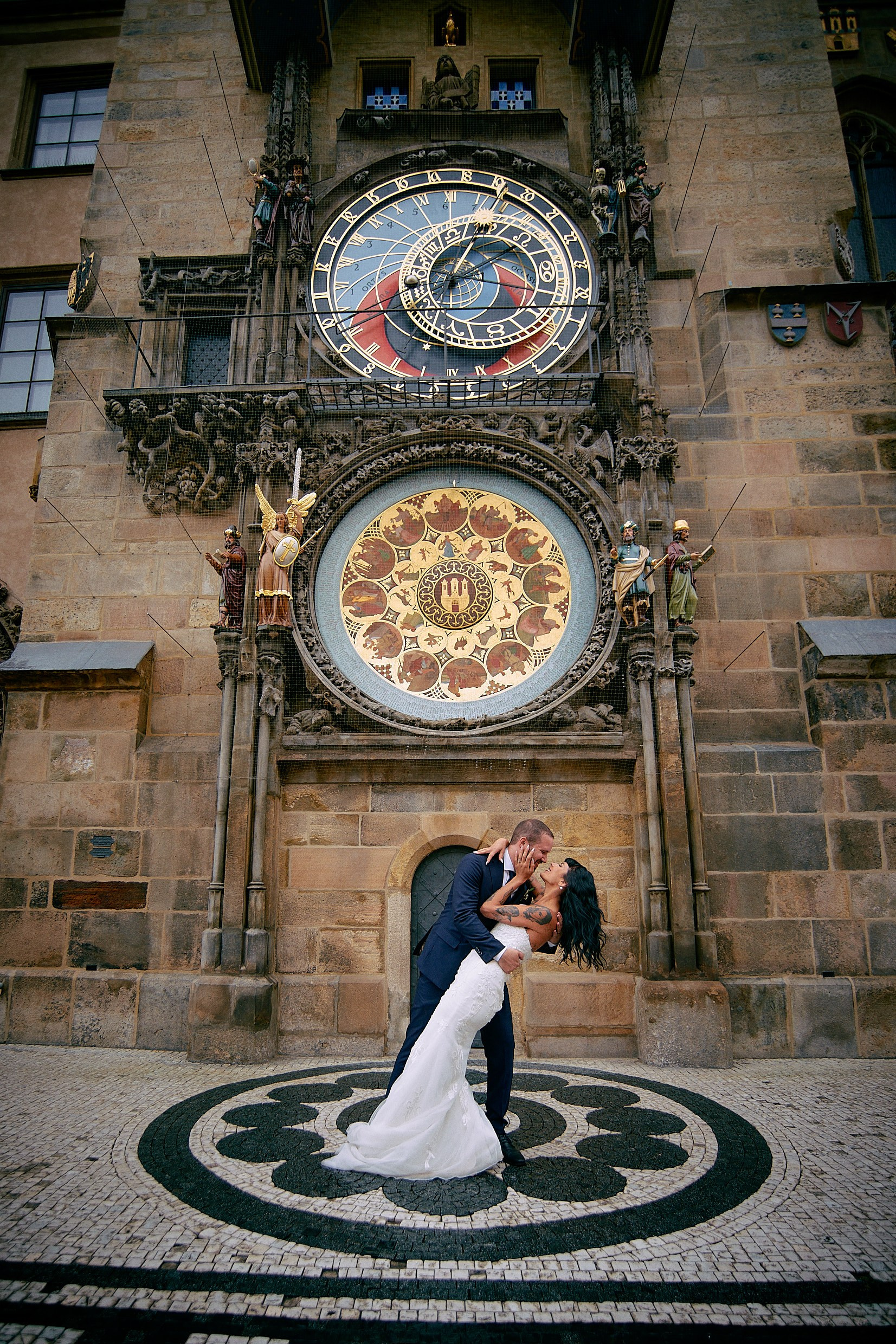 Bride kissing groom passionately during dip under Astronomical Clock.