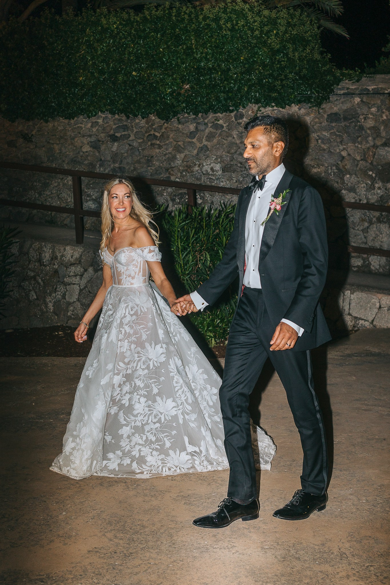 Bride and groom walking hand in hand at night during their Mallorca wedding reception