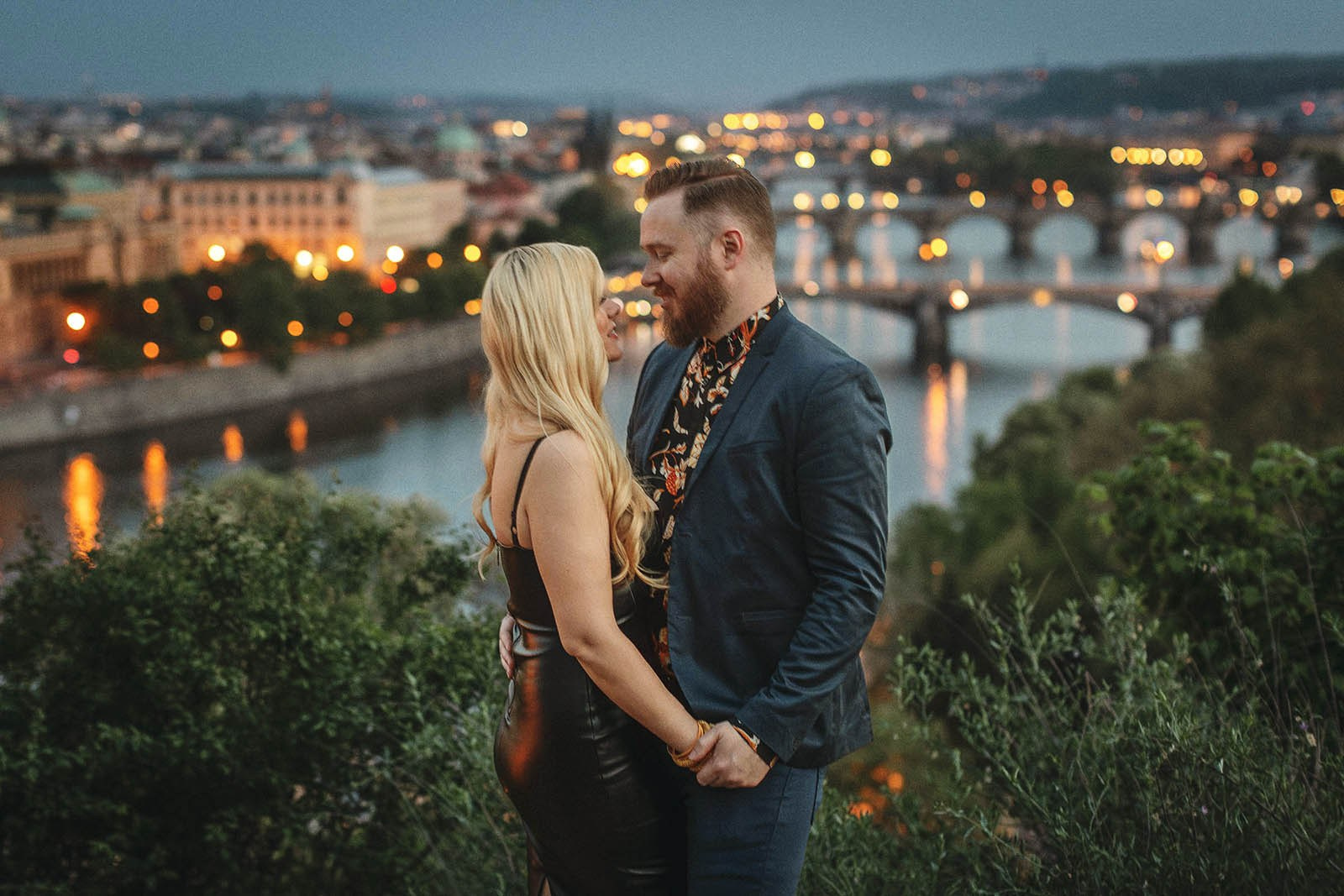 Couple embracing above the twinkling lights of Prague