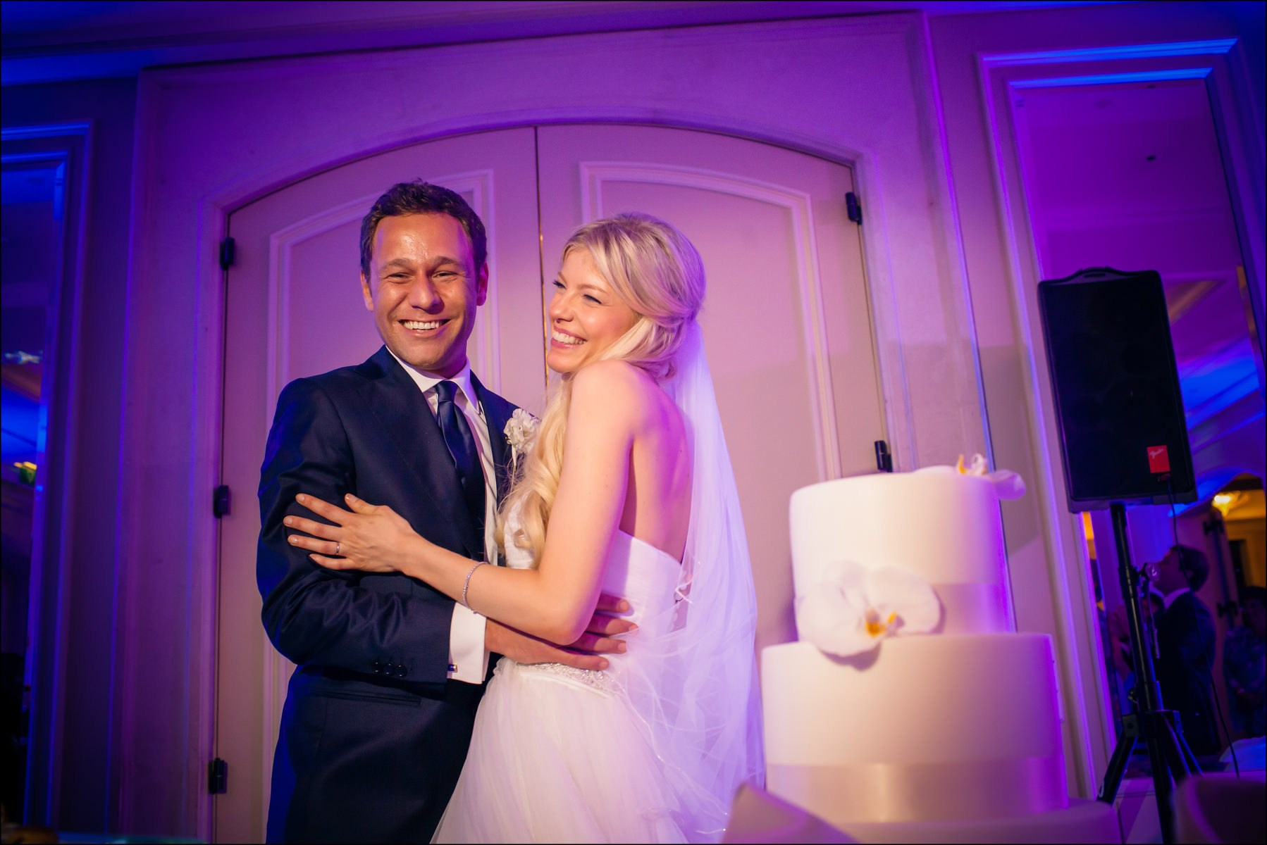 Happy couple beside three-tier wedding cake Prague reception
