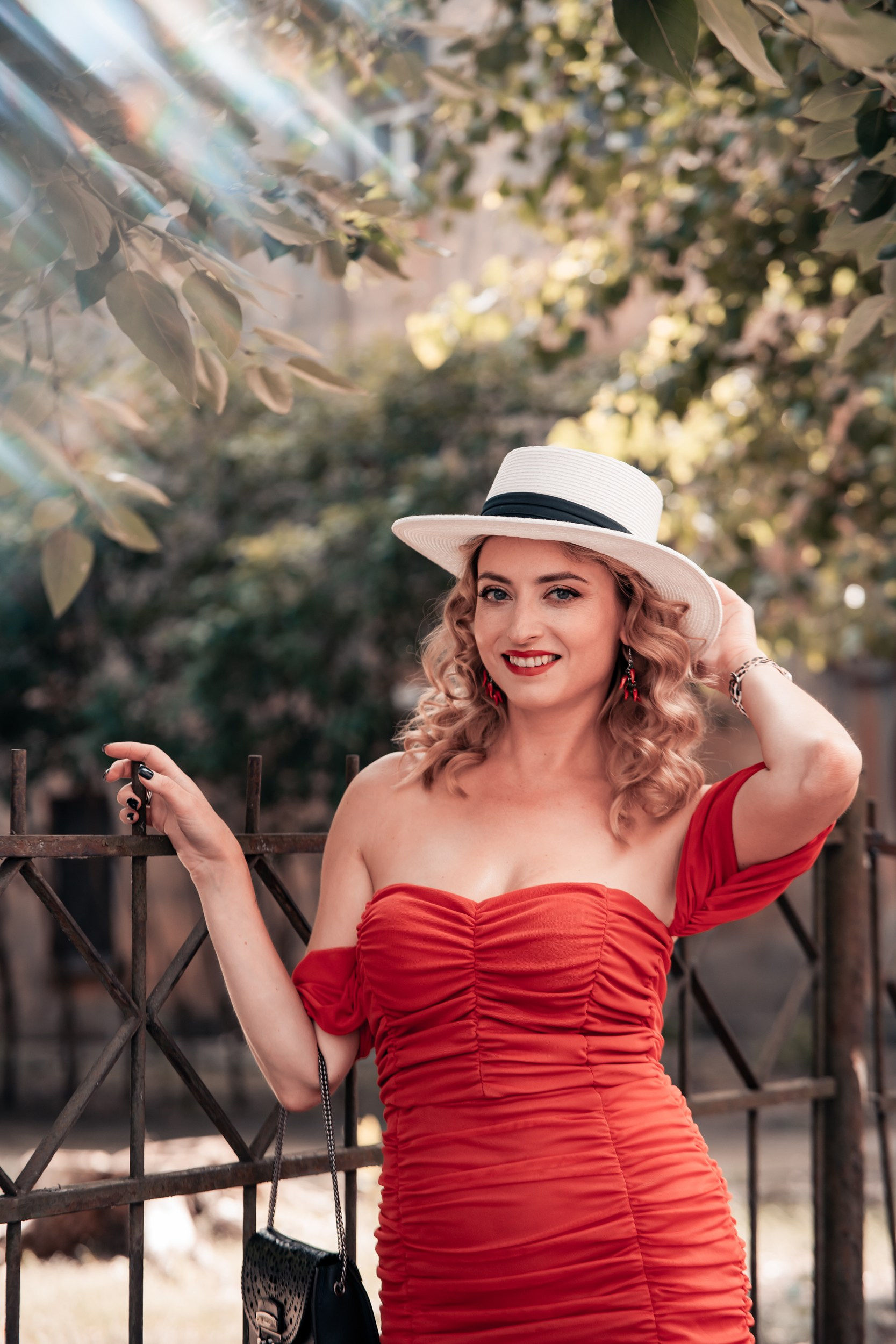 A woman in a beautiful red dress stands in the sunshine, Riga photographer for portraits
