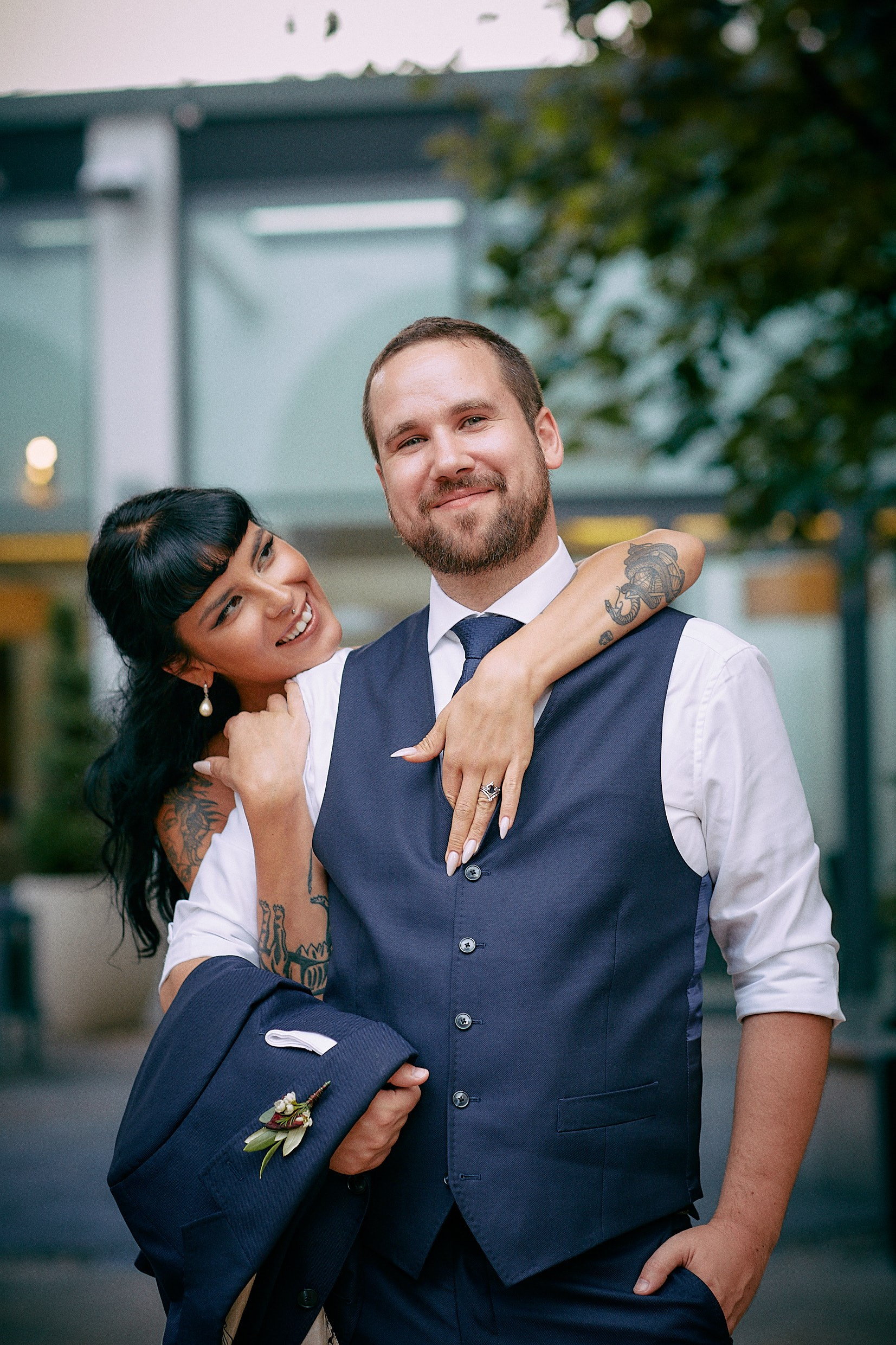 Bride hugging groom from behind playfully in garden setting.