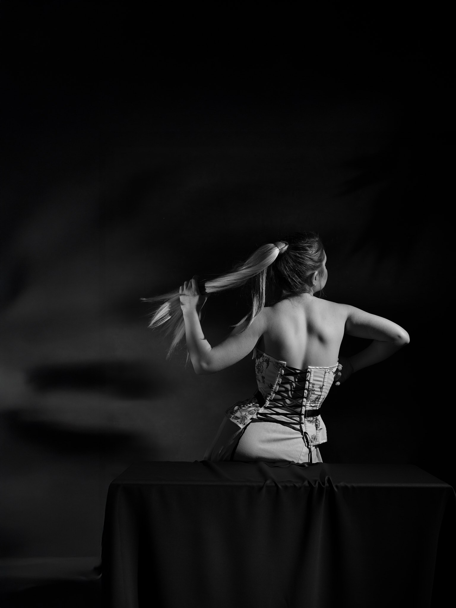 Fine art black and white photograph of a woman in a corset, studio lighting, inspired by Horst P. Horst and early 20th century fashion imagery.