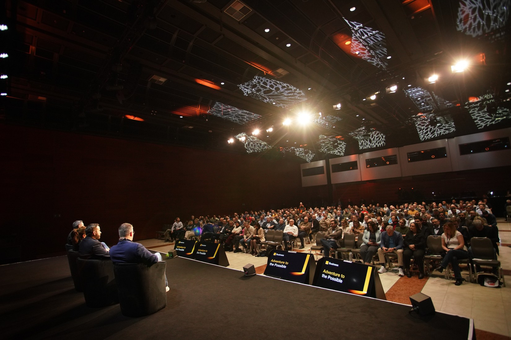 Wide-angle shot of panel discussion on stage with large audience at Orange Business conference, Hilton Prague corporate event photography.