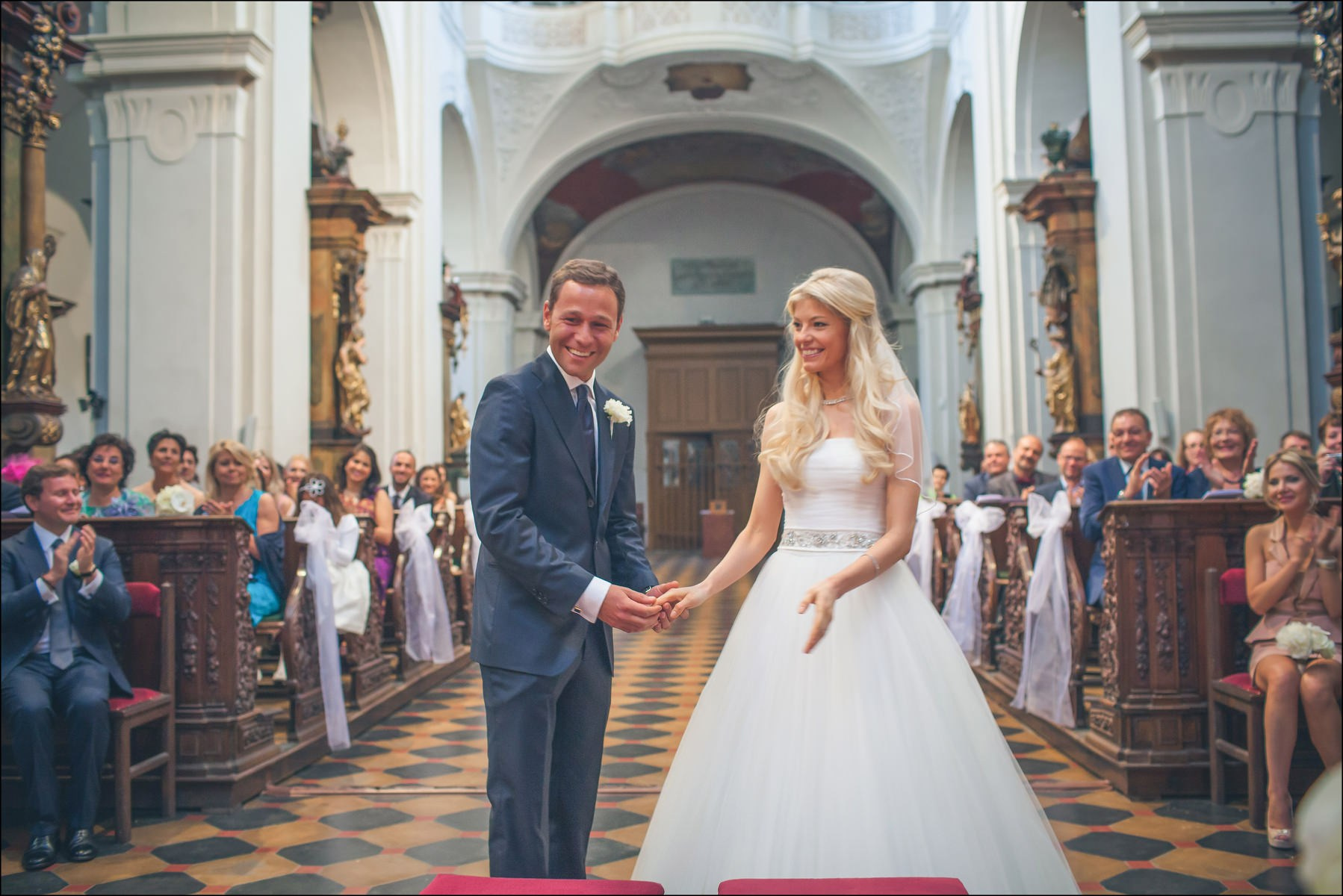 Smiling groom Sergio holding bride's hand post-ceremony St. Thomas Prague
