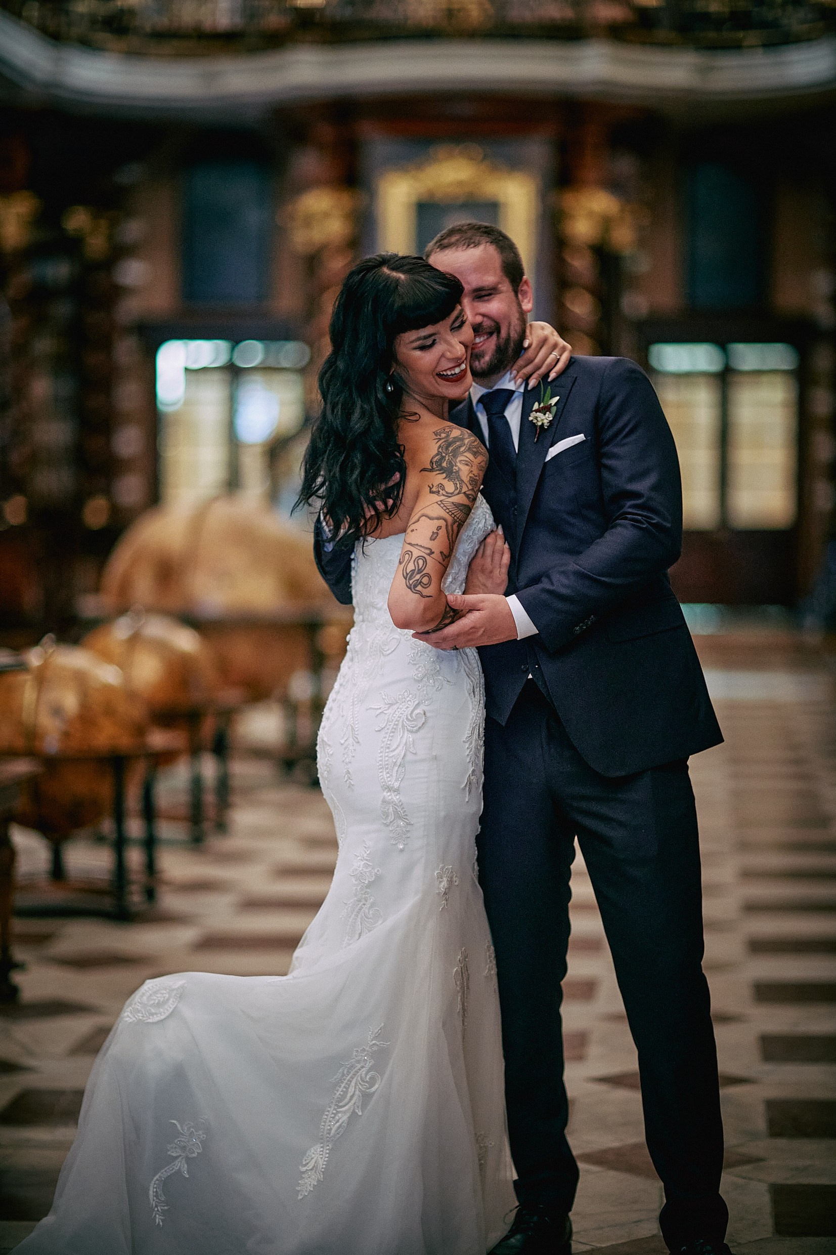 Tattooed bride lifting gown teasingly in historic library with groom.