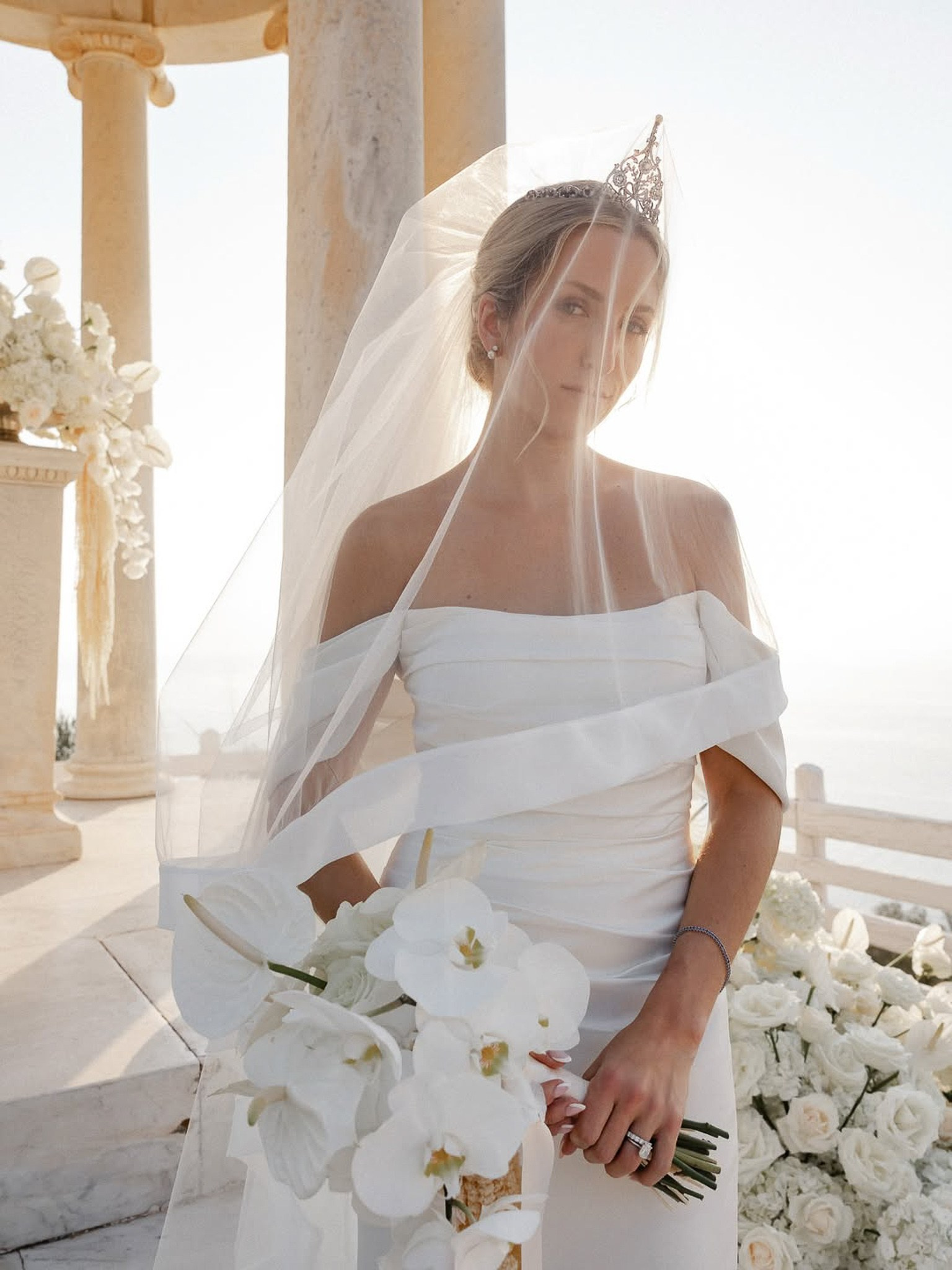 Close-up portrait of the bride in her veil and tiara holding a white orchid bouquet at Son Marroig