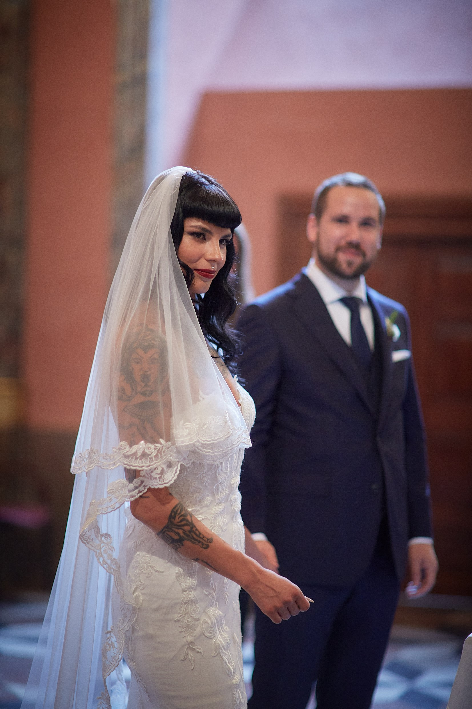 Emotional tattooed bride tearing up beside groom during vows.