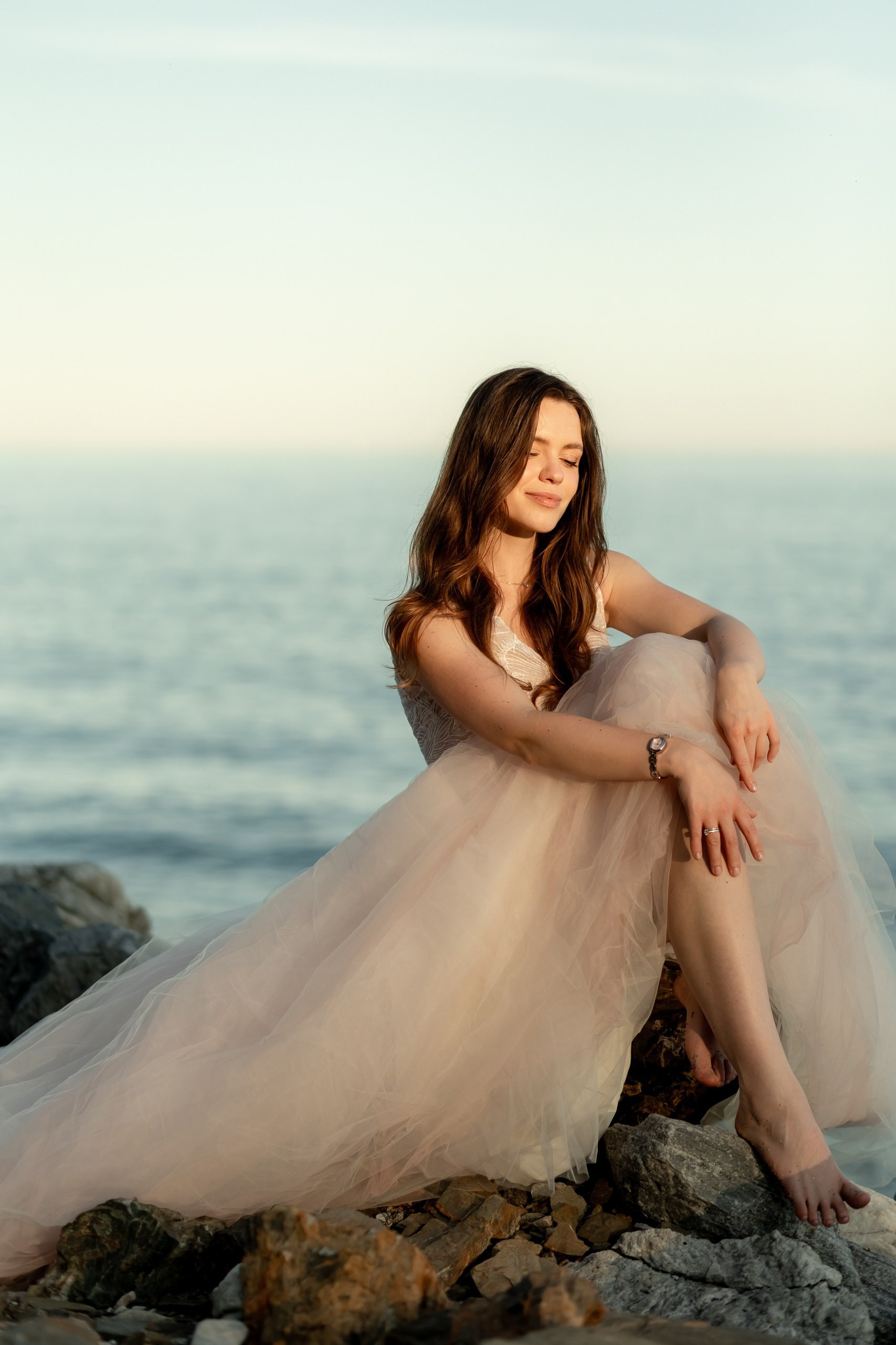 Braut sitzt solo auf Felsen, Brautkleid ausgebreitet, träumerisch, After Wedding Shooting Alicante Spanien