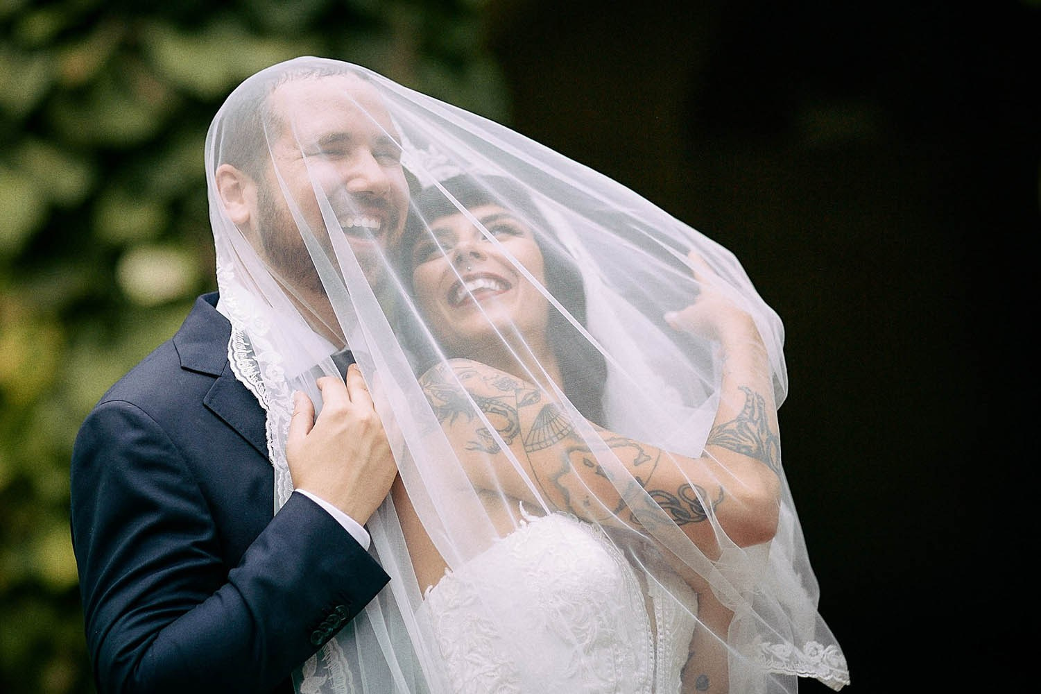 Bride draping veil romantically over groom in Grebovka cave setting.