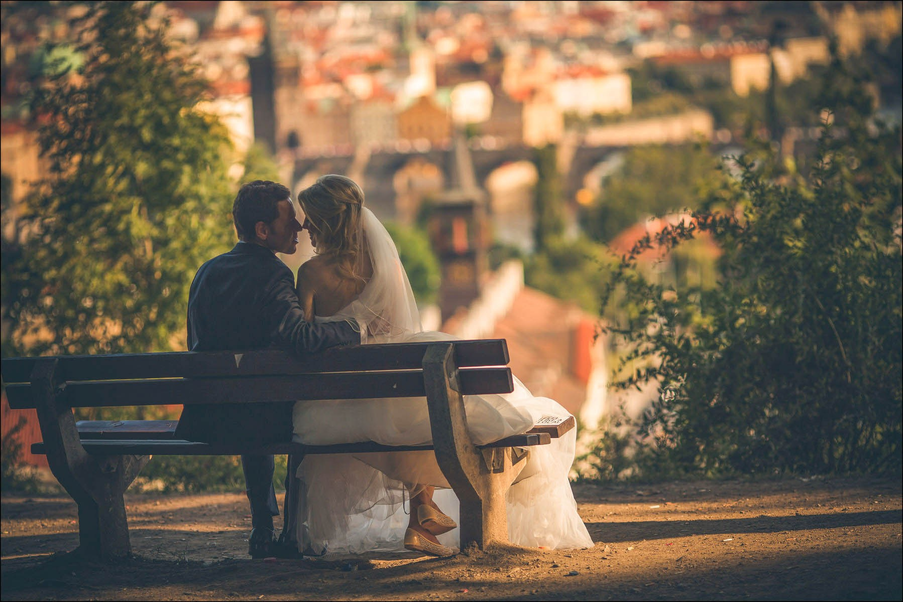Newlyweds resting on bench overlooking Prague valley golden hour