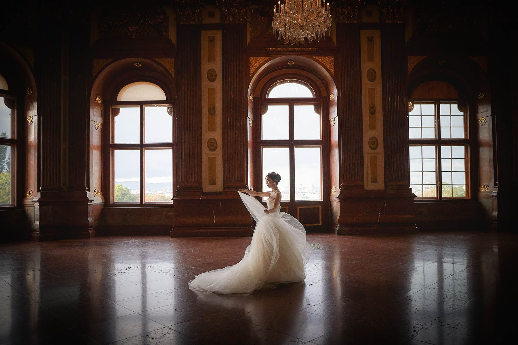 Bride walking through sunlit grand hall at Belvedere Palace.