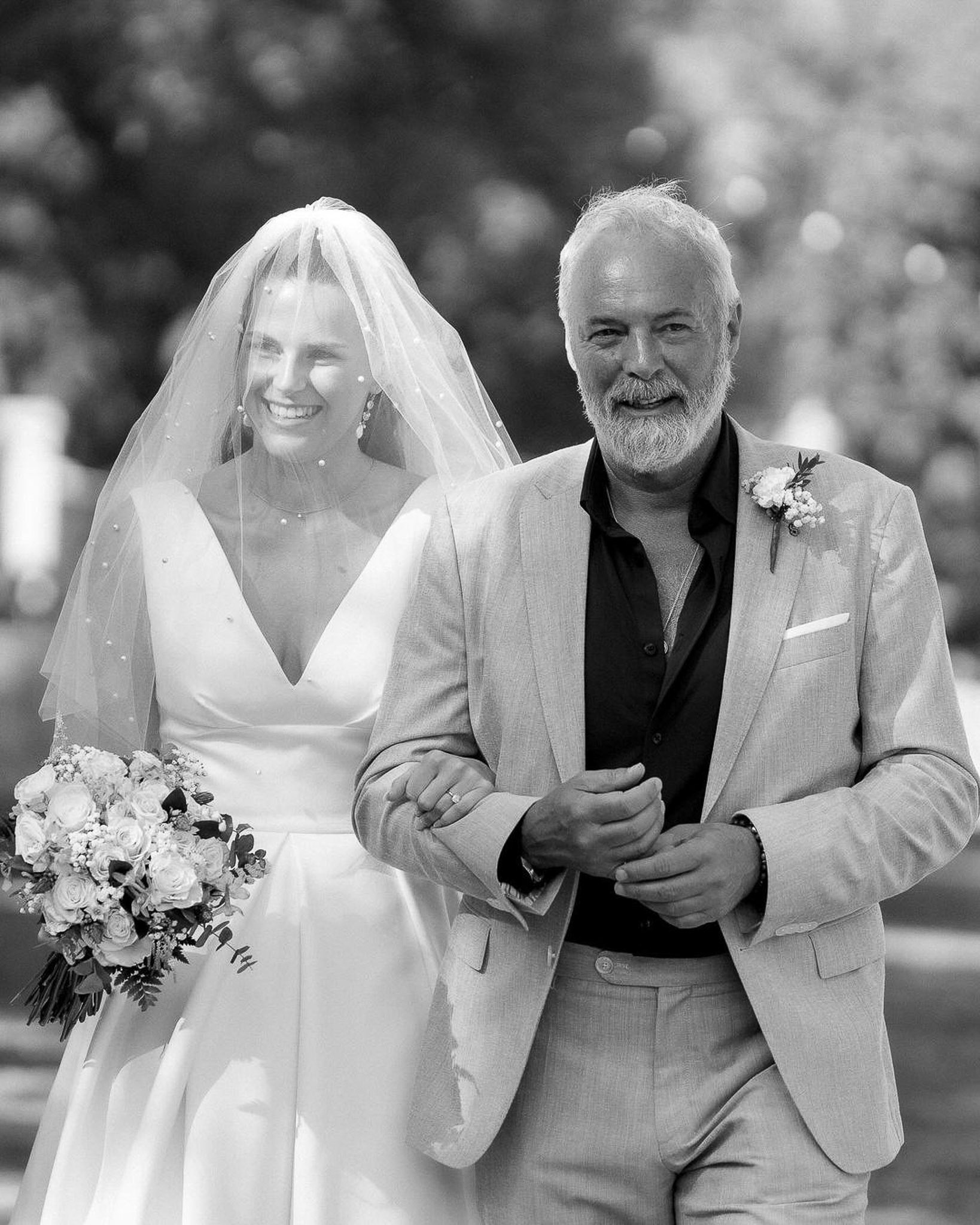 Bride laughing as she walks down the aisle with her father at her Mallorca wedding