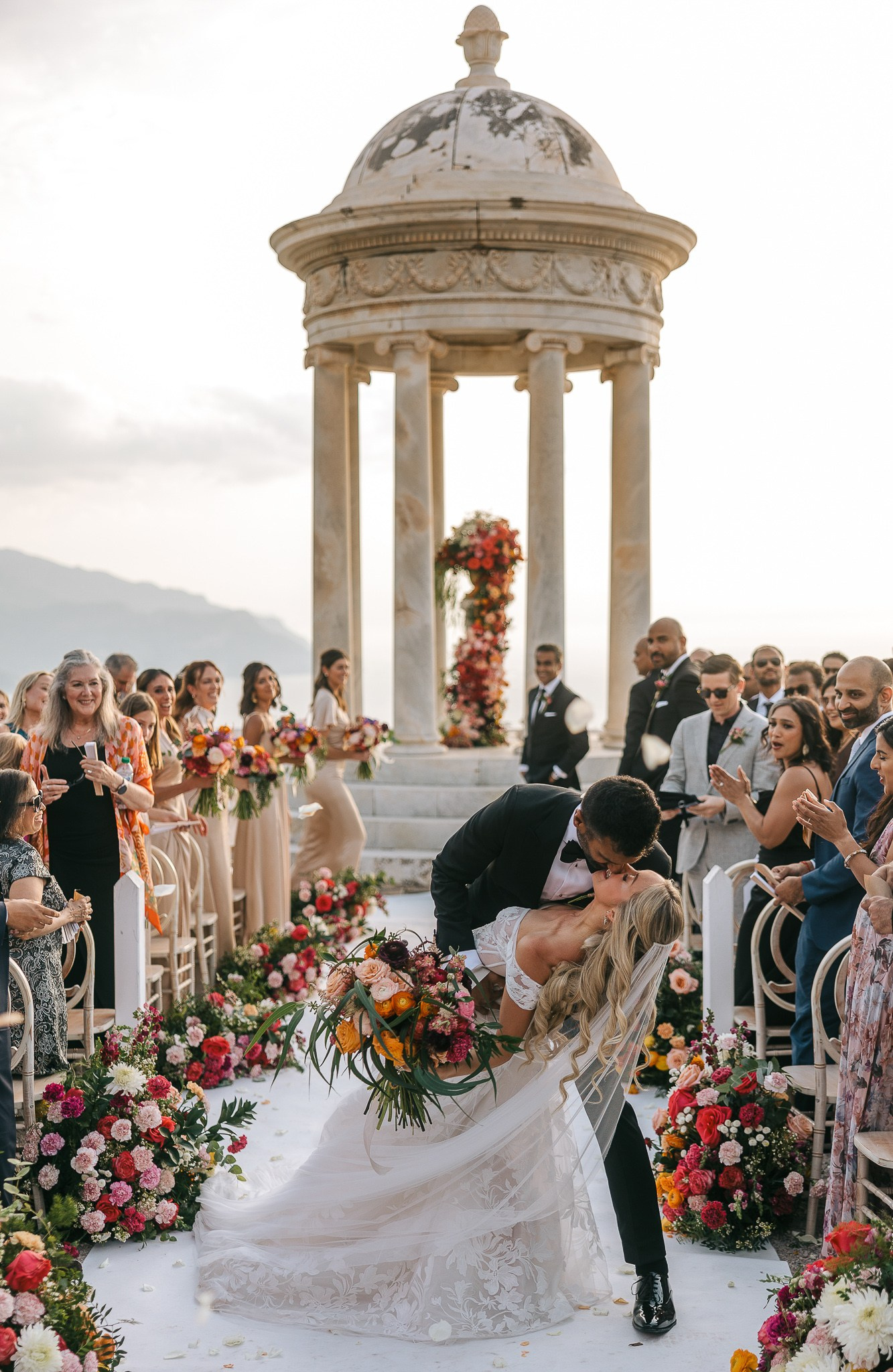 Groom dipping his bride for a kiss as guests celebrate at their Son Marroig wedding