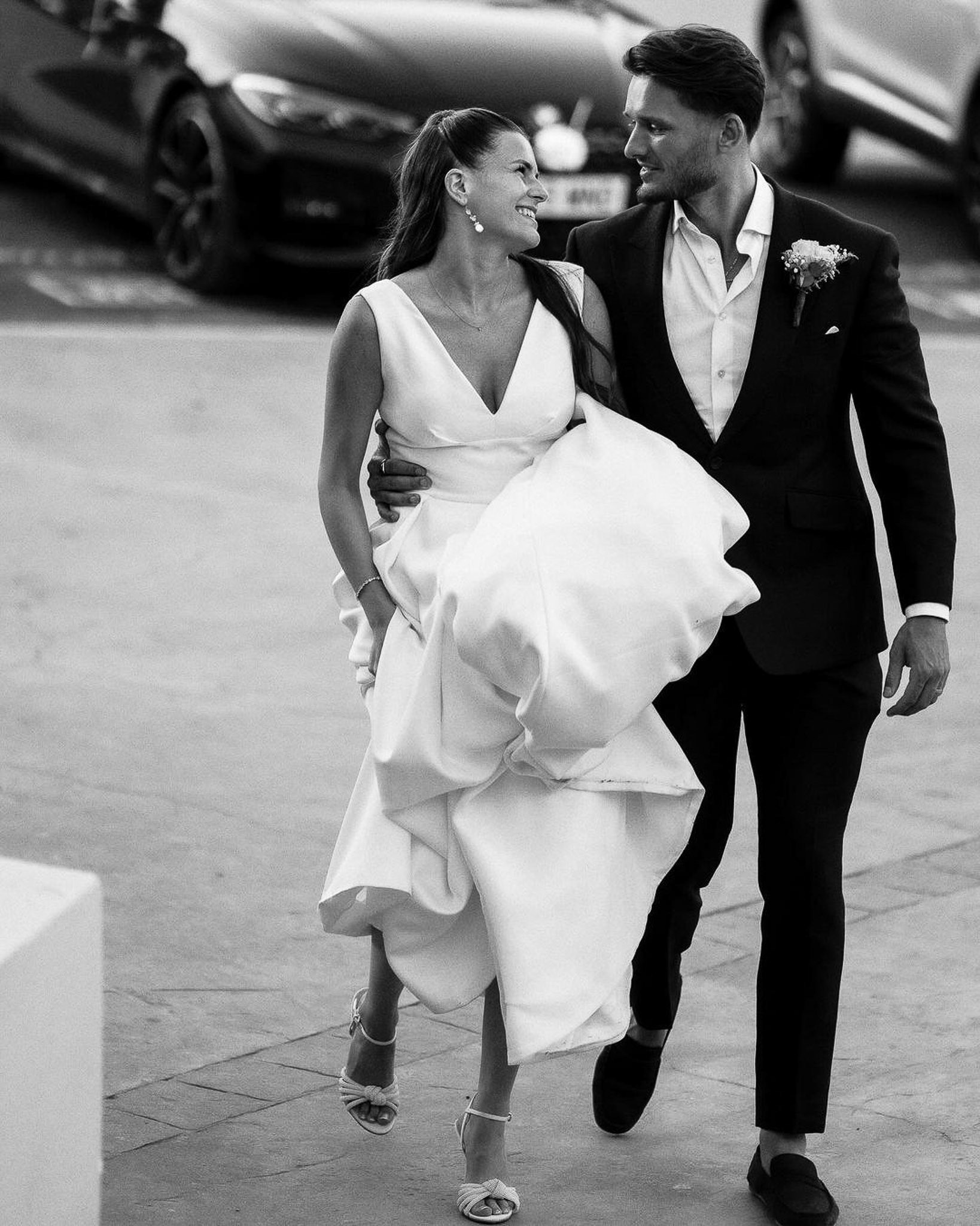 Groom carrying his bride's dress as they walk together after their Mallorca wedding