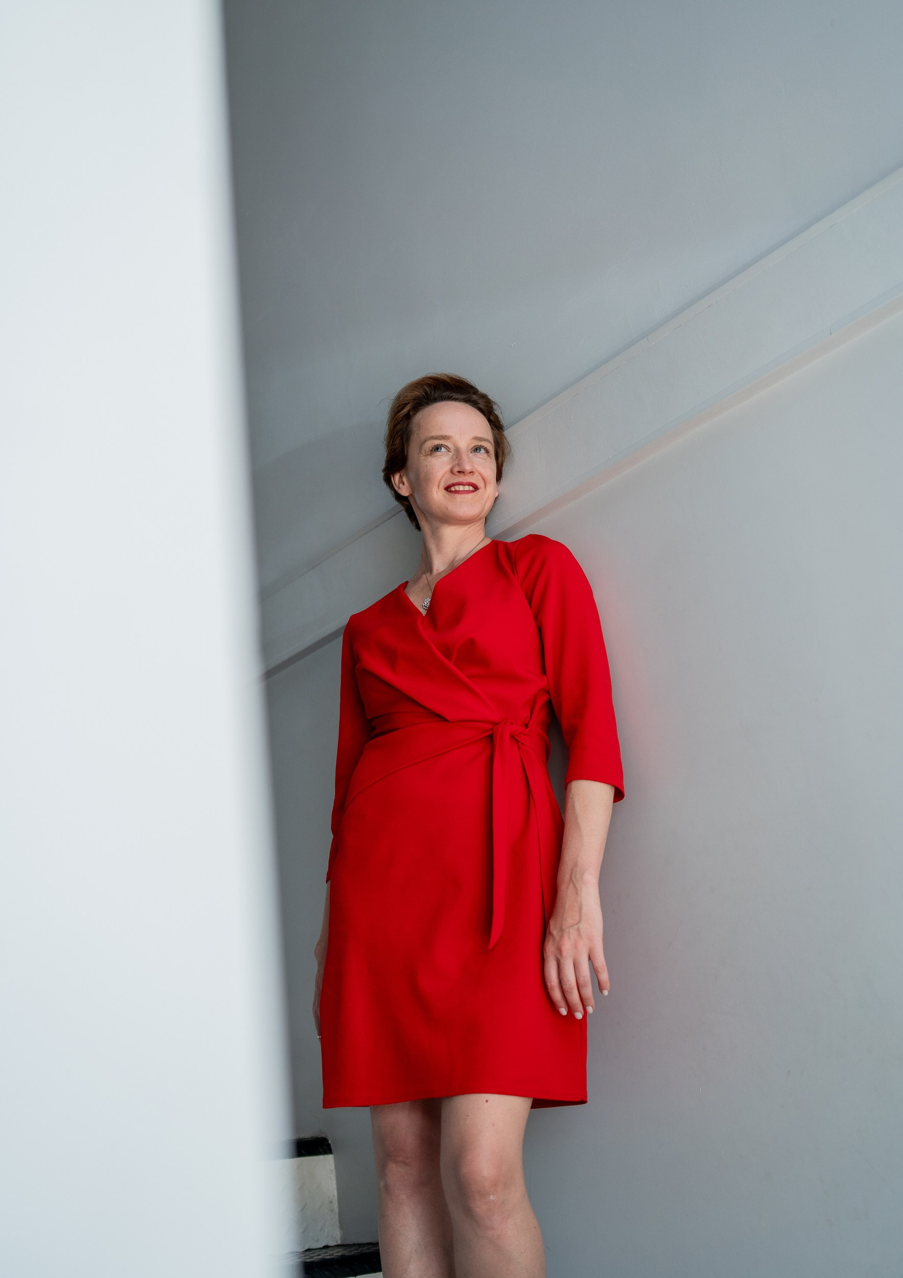 A woman in a red dress near the wall