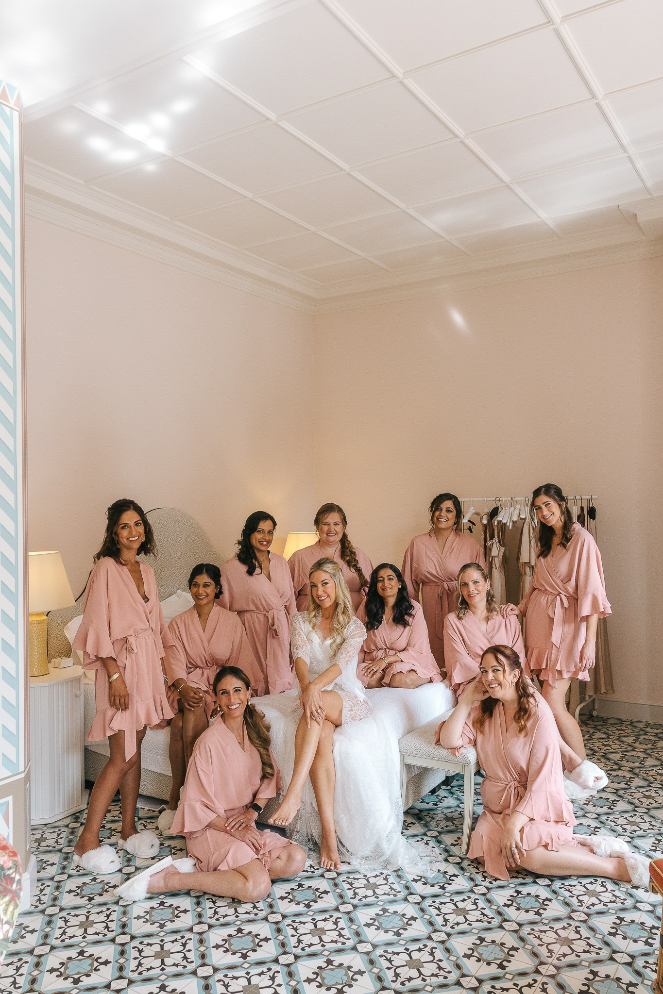 Bride and her bridesmaids in pink robes posing together before the wedding ceremony