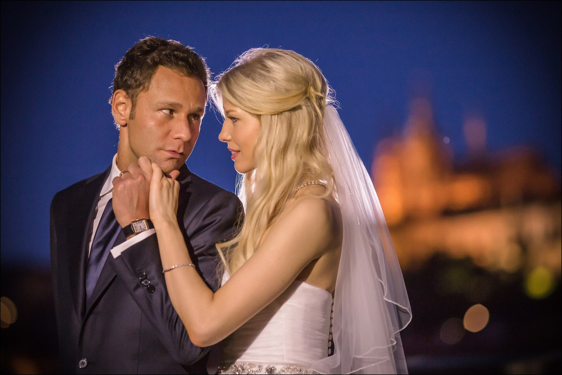 Groom kissing bride's hand romantic night portrait Prague Castle view