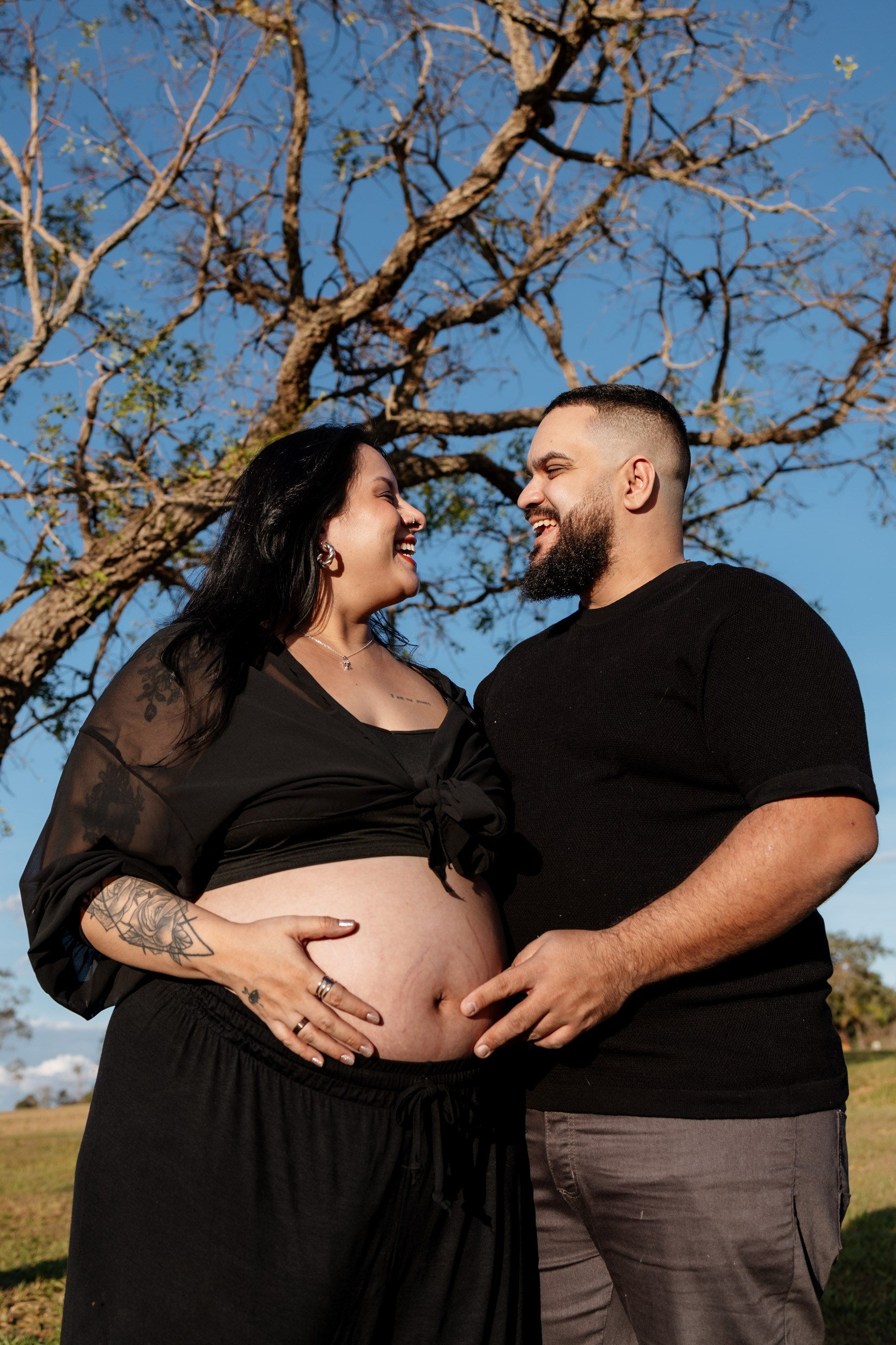 Casal se olha com carinho durante ensaio de maternidade