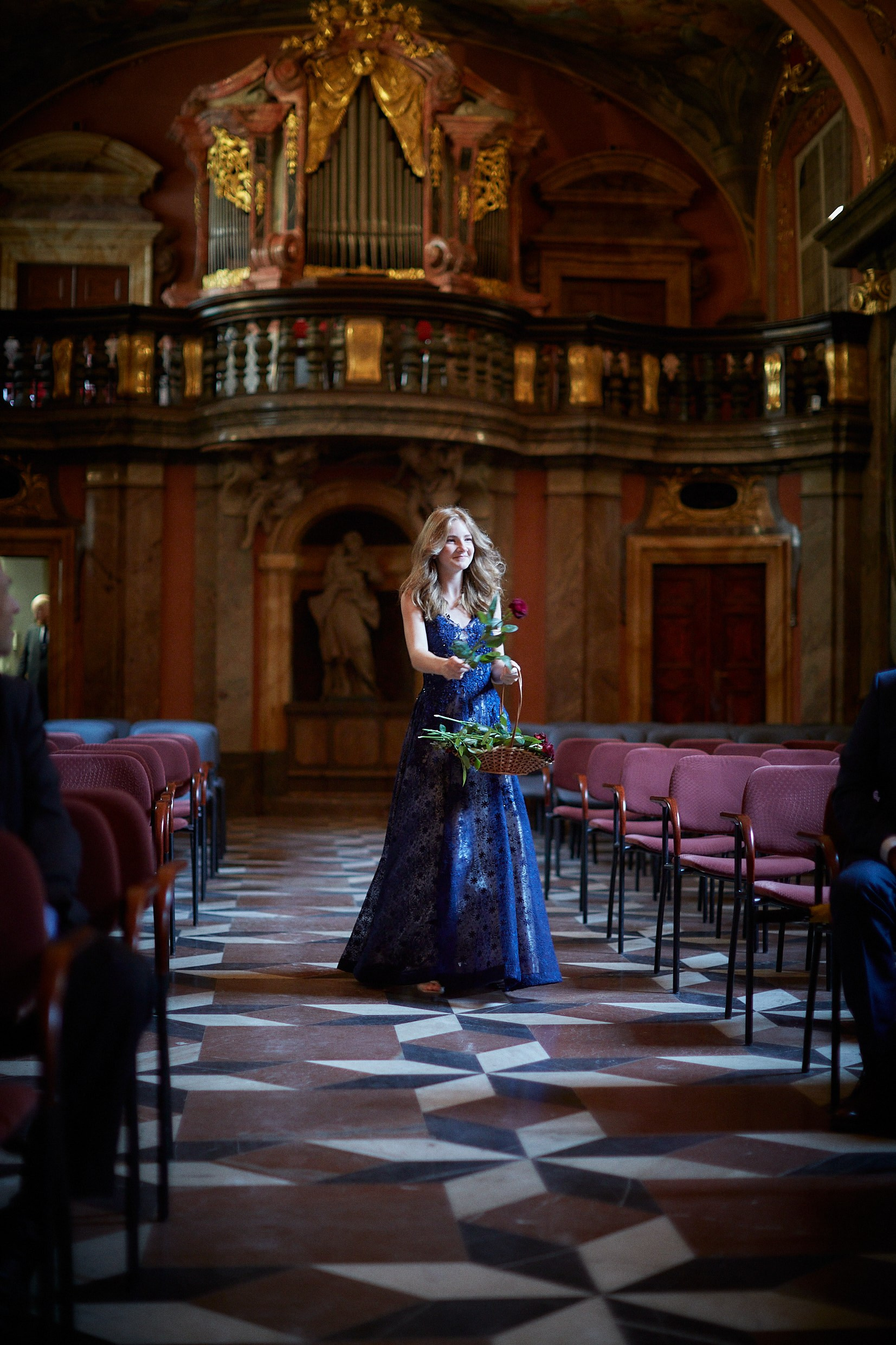 Young flower girl processing down baroque Mirror Chapel aisle.