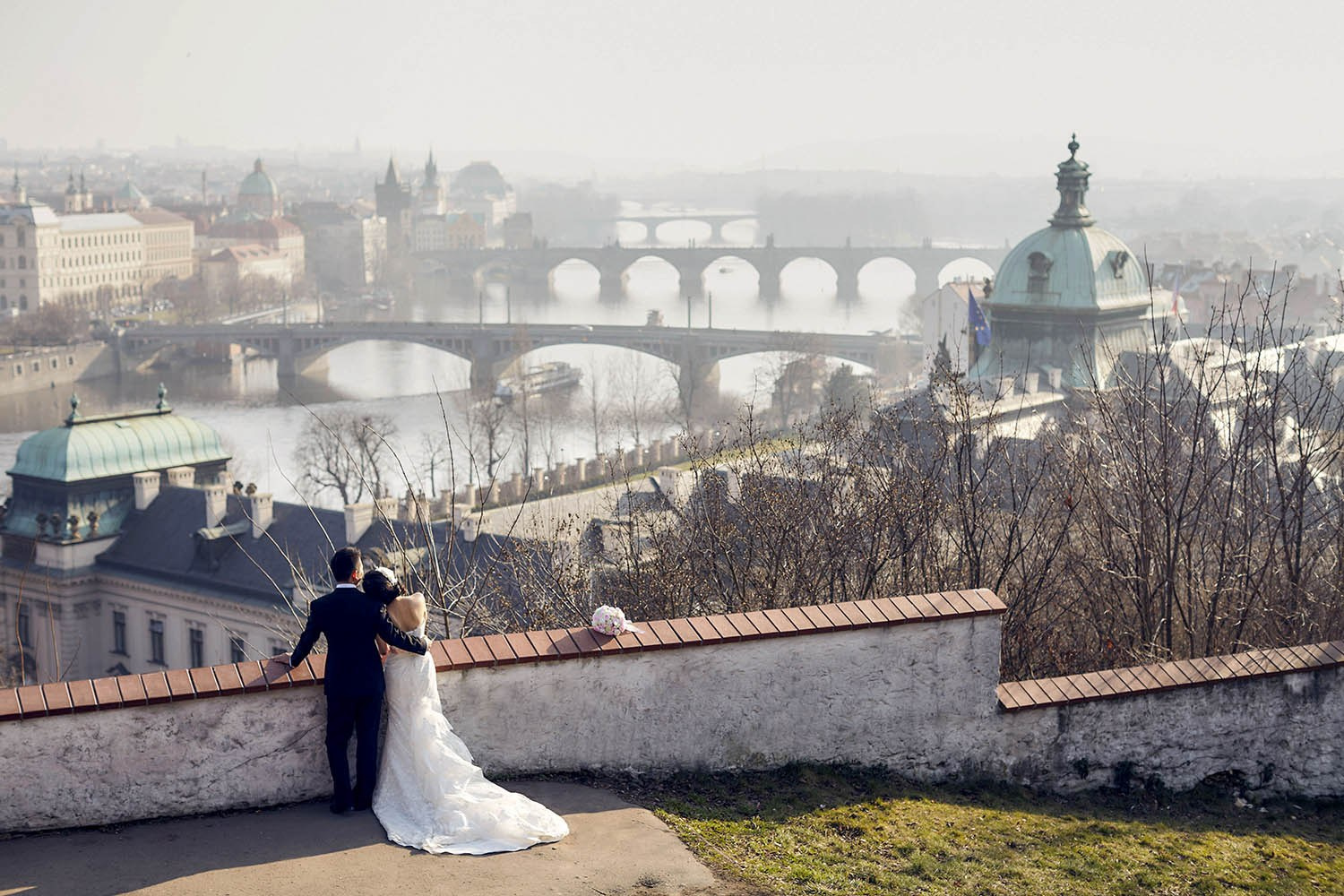 Asian newlyweds view the historic city of Prague as a foggy mist shrouds the city