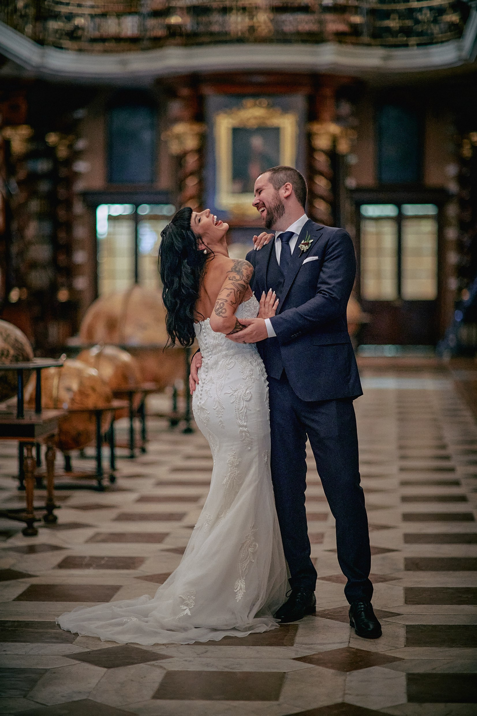 Newlyweds embracing amid ornate Klementinum Library architecture.